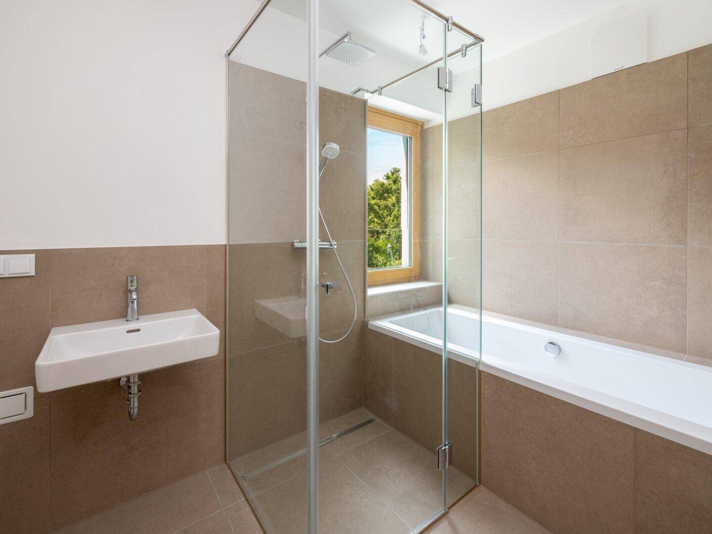Modernes Badezimmer mit Badewanne, ebenerdiger Dusche, Fenster und beigen Fliesen.