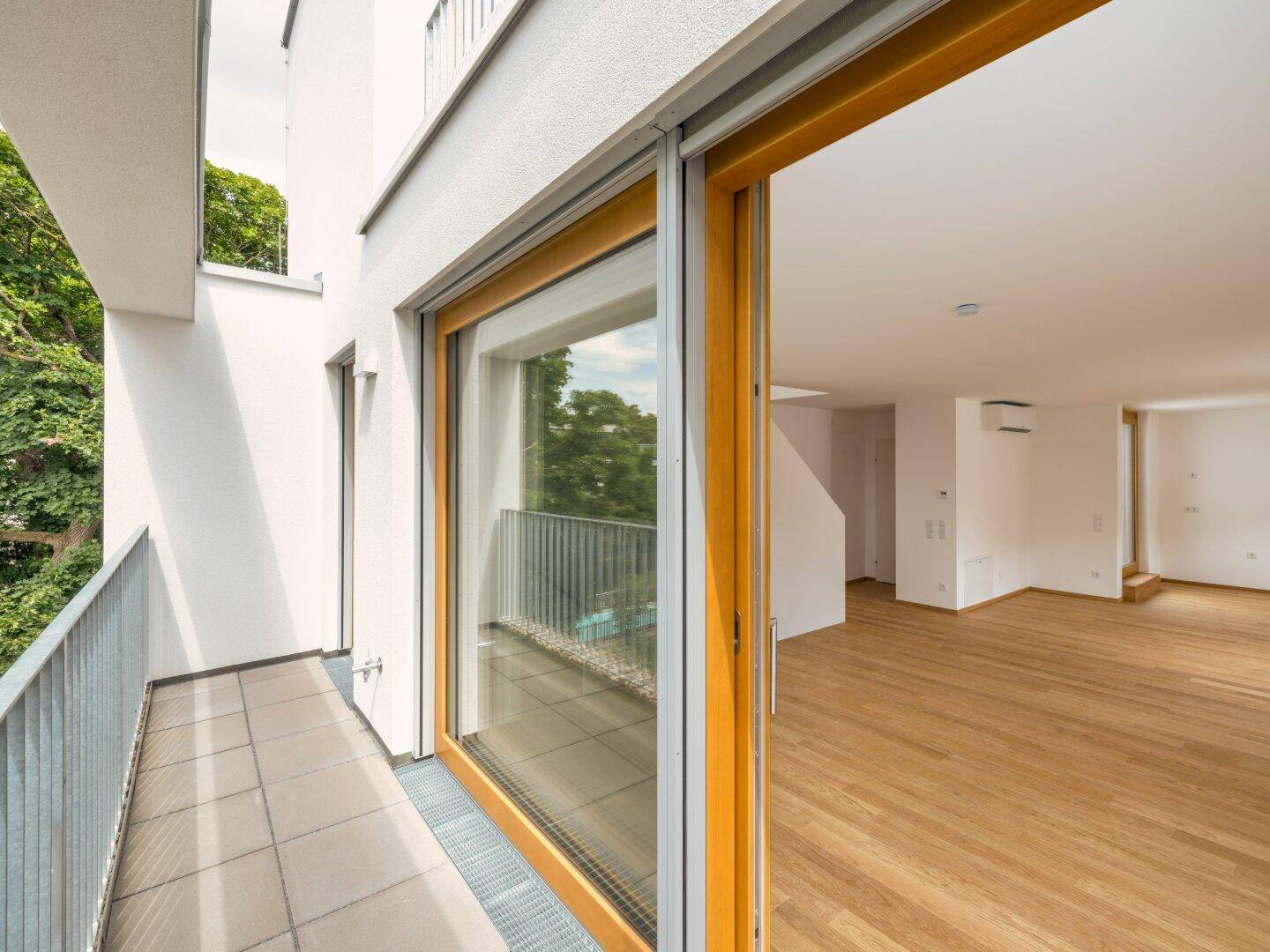 Heller Balkon mit Fliesenboden und Blick ins Grüne, zugänglich vom Wohnbereich.