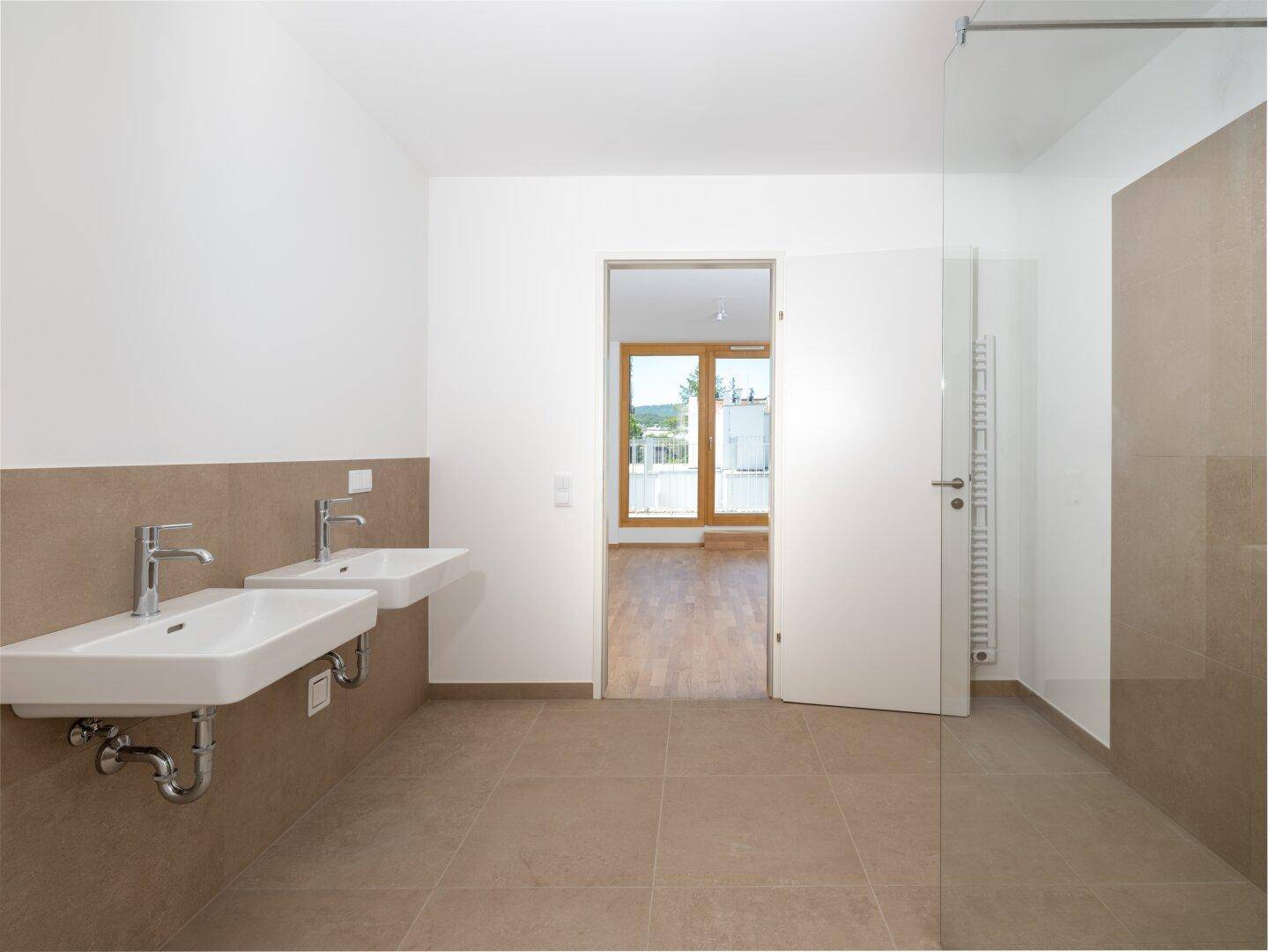 Modernes Badezimmer mit Doppelwaschbecken, ebenerdiger Dusche und beigefarbenen Fliesen.