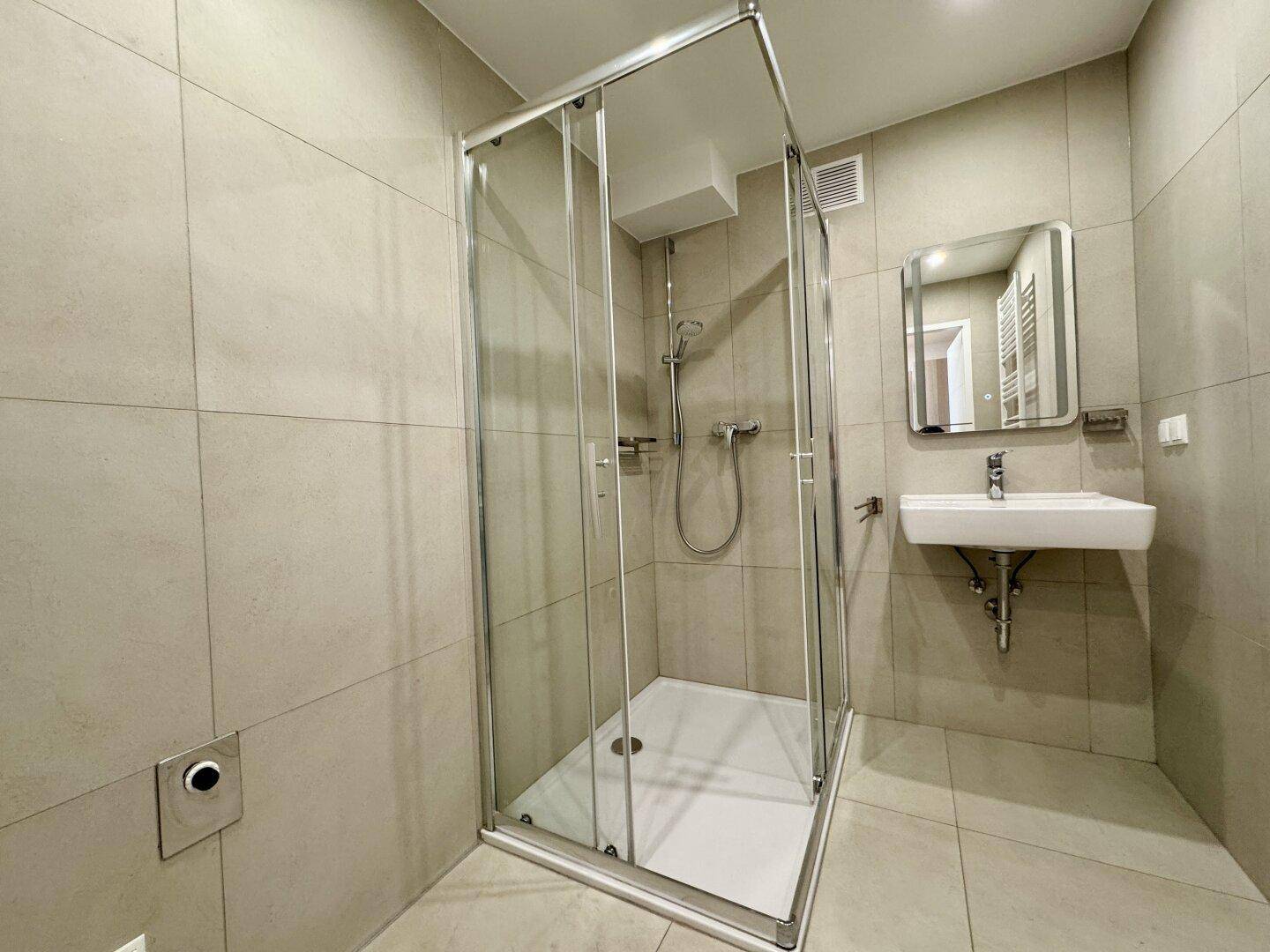 Helles Badezimmer mit modernen Fliesen, Glasduschkabine und Wandwaschbecken.
