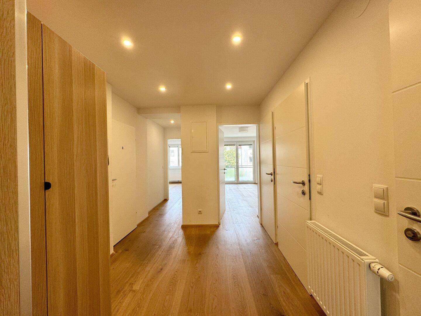 Geräumiger Eingangsbereich mit Holzboden, praktischen Einbauschränken und Zugang zu den Zimmern.
