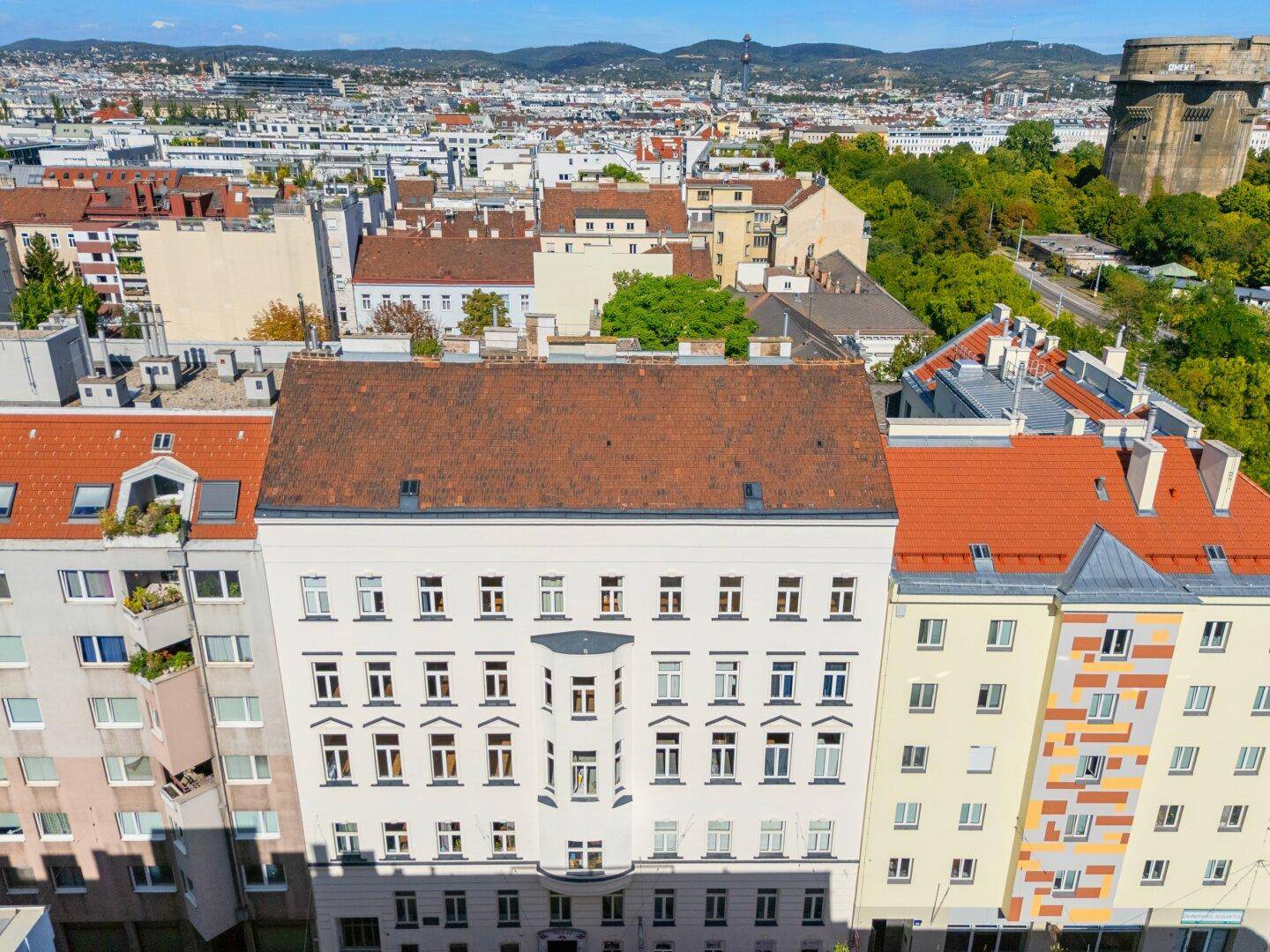 Luftaufnahme eines Wohngebäudes mit rotem Ziegeldach und Stadtblick.