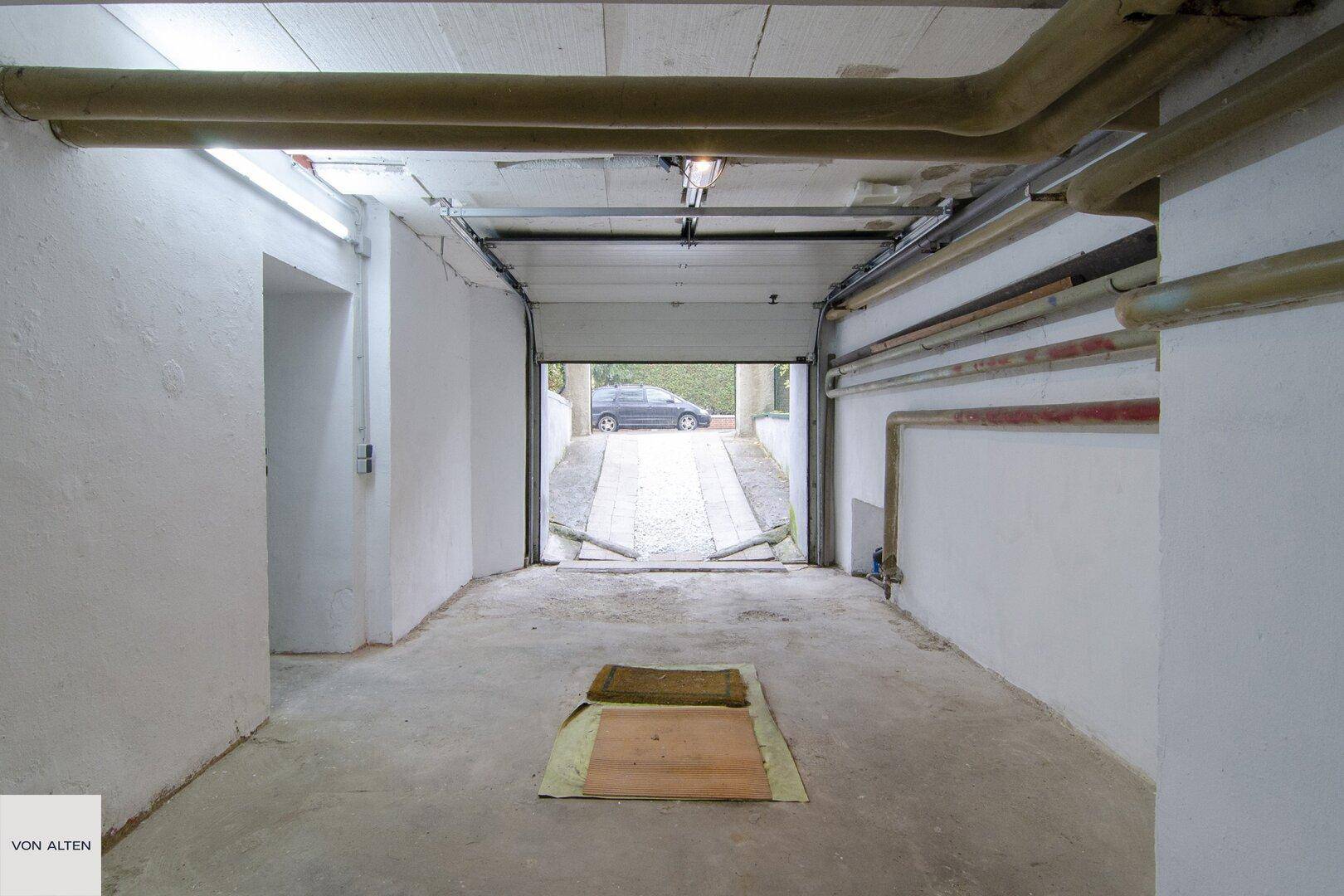 Geräumige Garage mit Betonboden und Zufahrt zur Straße, bietet Platz für Fahrzeuge.