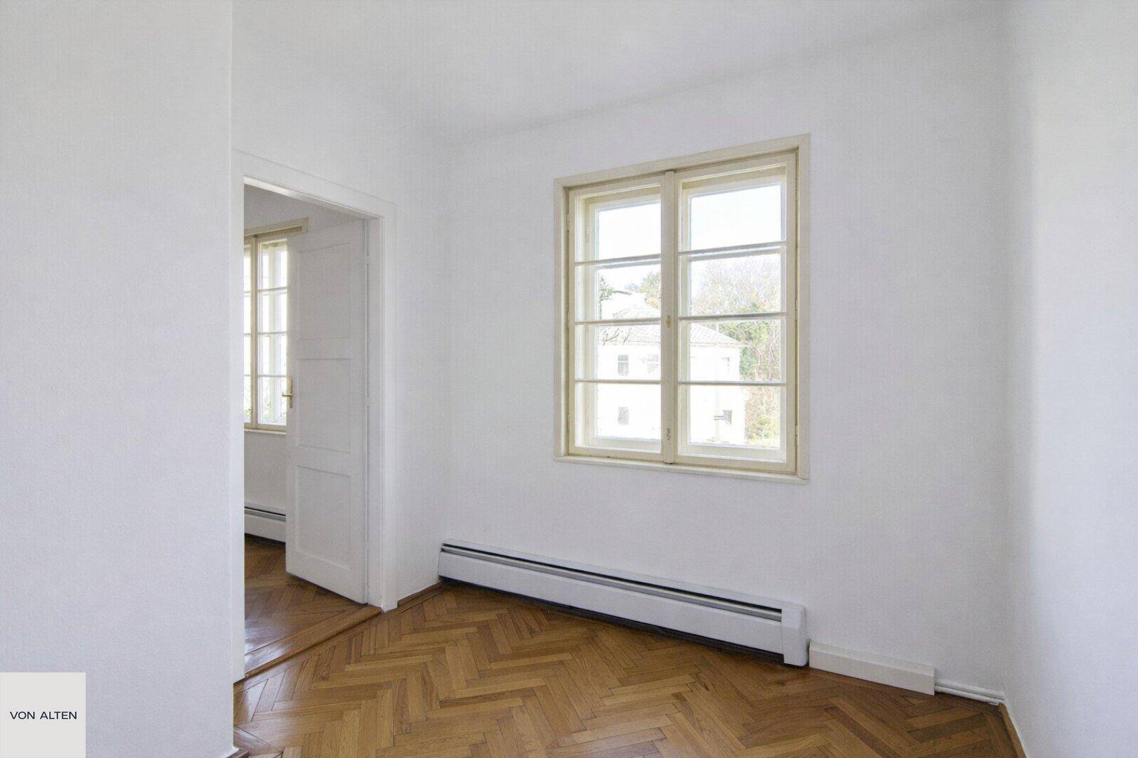Schlafzimmer mit Parkettboden und Zugang zu einem weiteren hellen Raum.