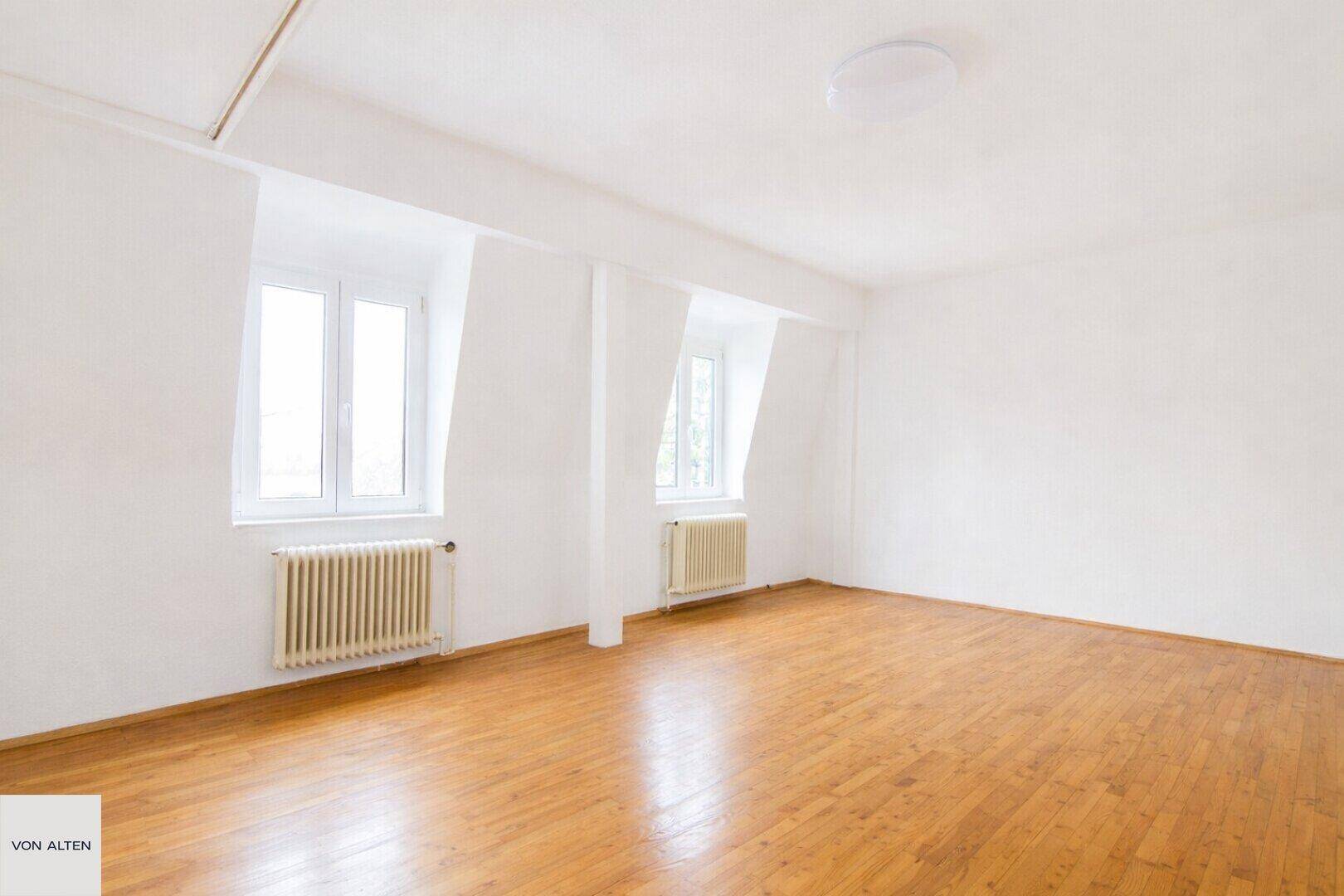 Helles Zimmer mit Holzboden und Dachschrägenfenstern, geeignet als Schlafzimmer im oberen Stockwerk.