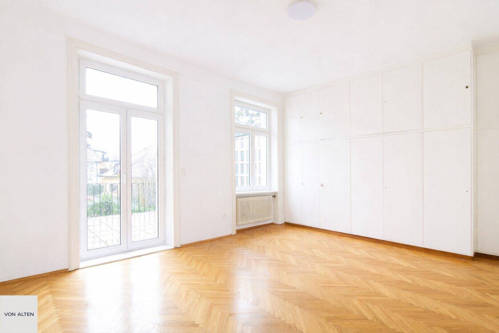 Helles Schlafzimmer mit praktischen Einbauschränken und Zugang zu einem französischen Balkon.