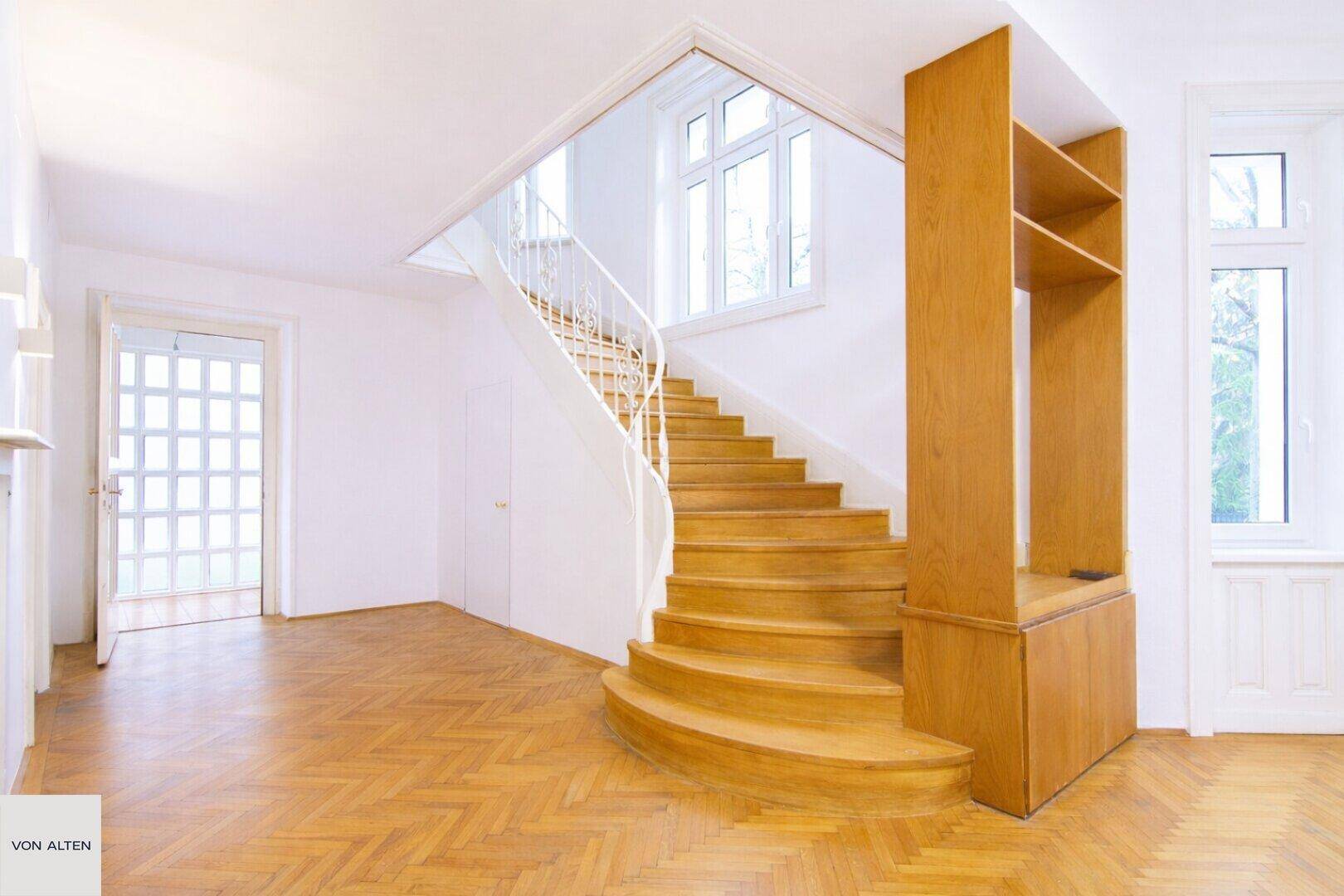 Helle Diele mit eleganter Holztreppe und integriertem Bücherregal, bietet viel Stauraum.