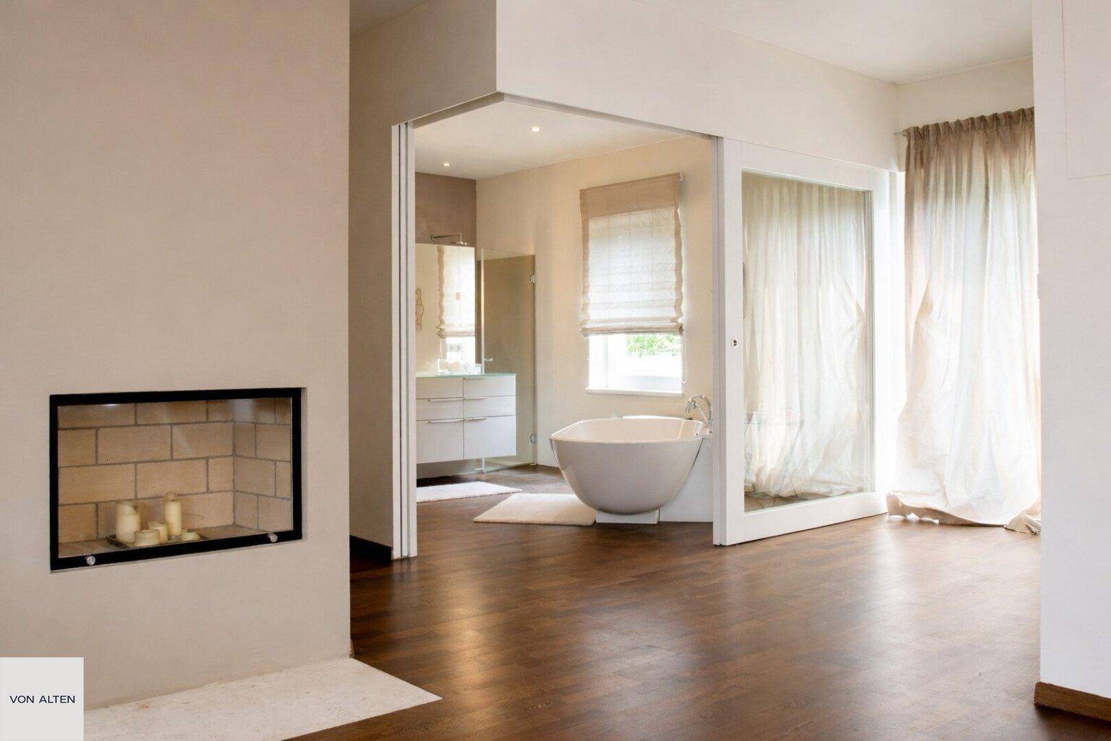 Schlafzimmer mit integriertem Kamin und offenem Zugang zu einem modernen Badezimmer.