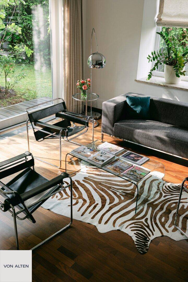 Detailansicht des Wohnzimmers mit Zebra-Teppich, Couch und Design-Sesseln.