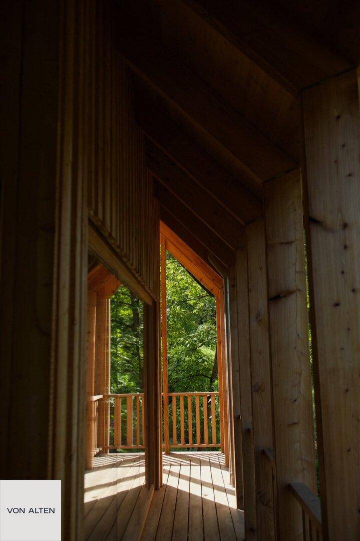 Überdachter Holzbalkon mit Blick ins Grüne, der zum Entspannen einlädt.