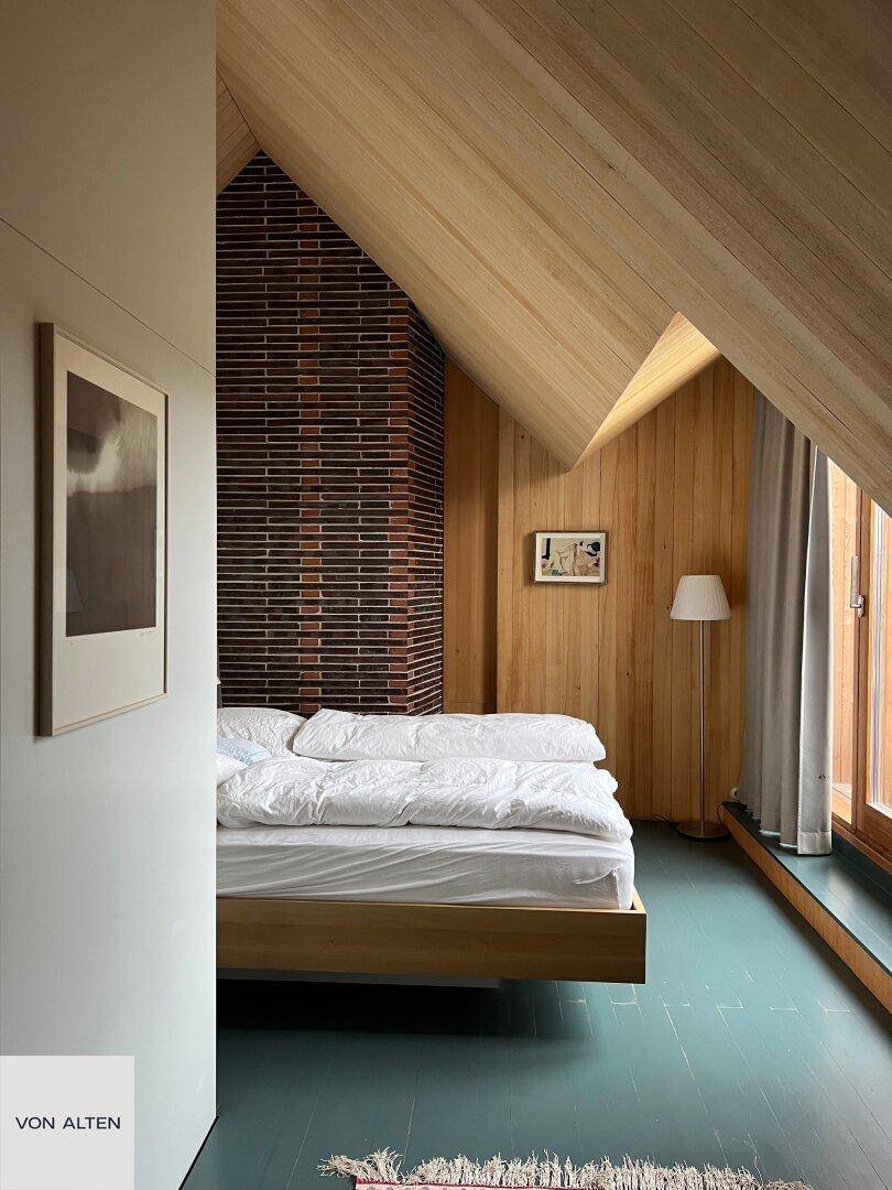 Gemütliches Schlafzimmer mit schrägen Holzwänden, Ziegelakzenten und Holzboden.