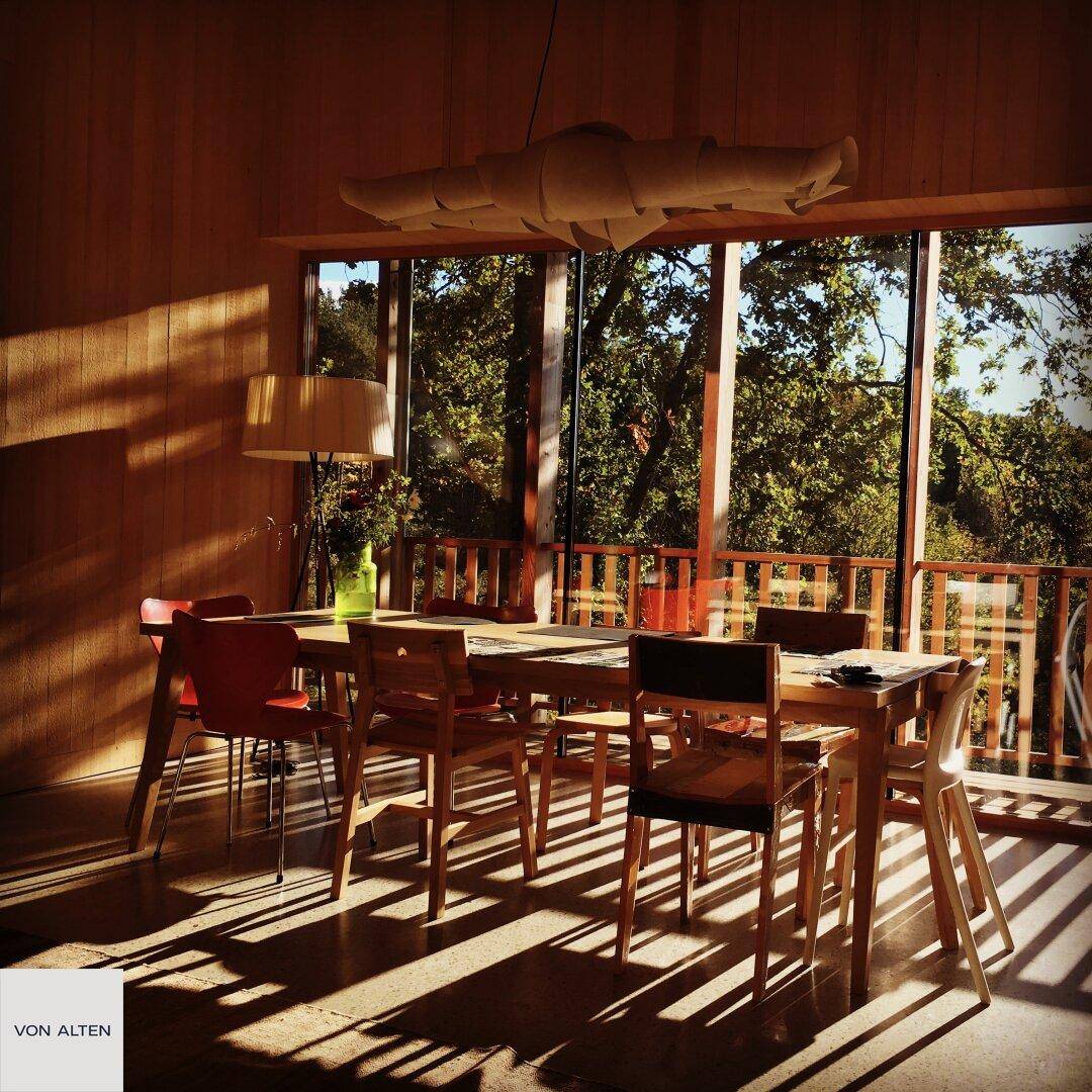 Sonnenverwöhnter Essbereich mit Holztisch und Stühlen, durchflutet von natürlichem Licht.