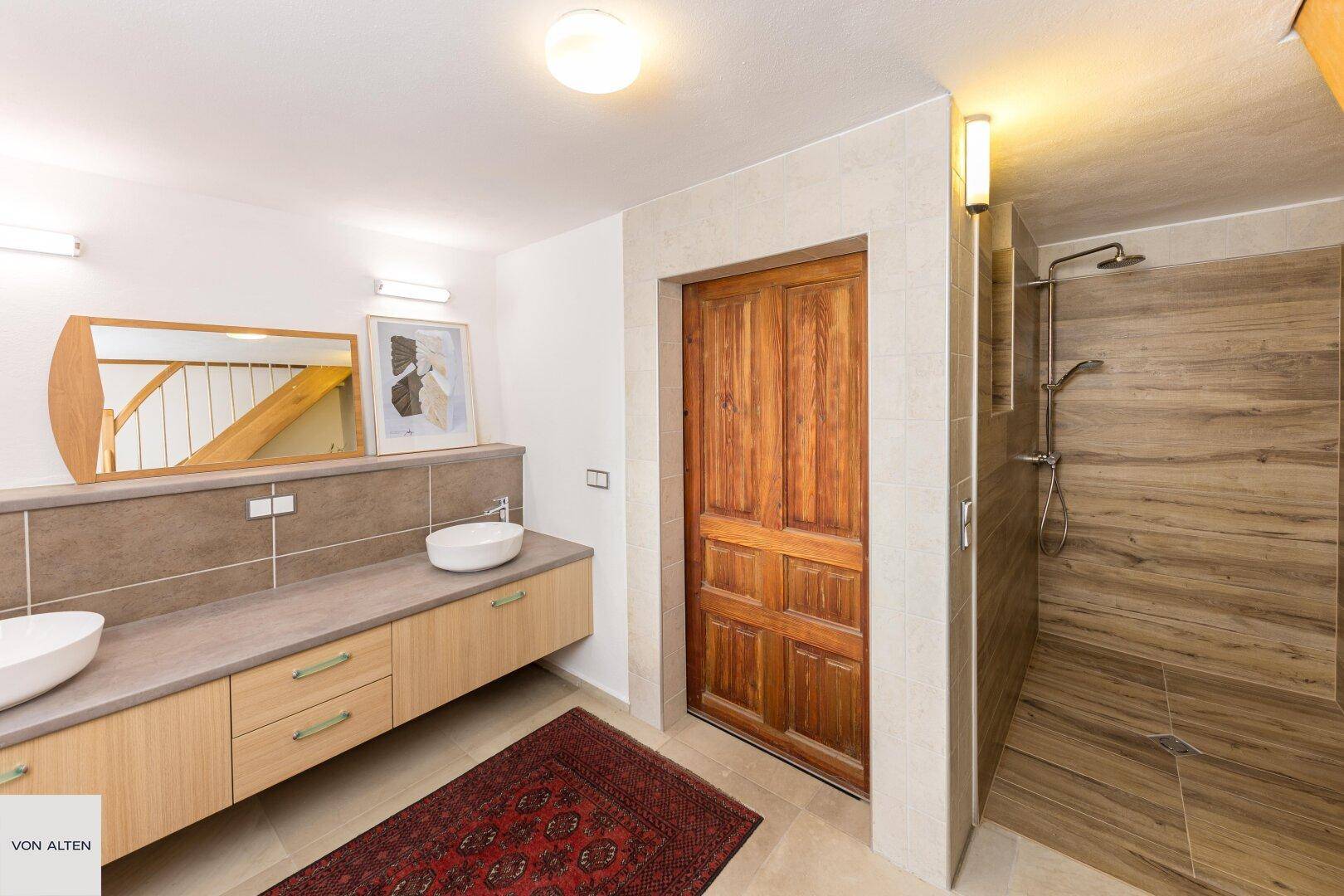Modernes Badezimmer mit Doppelwaschbecken, begehbarer Dusche und Holzakzenten.