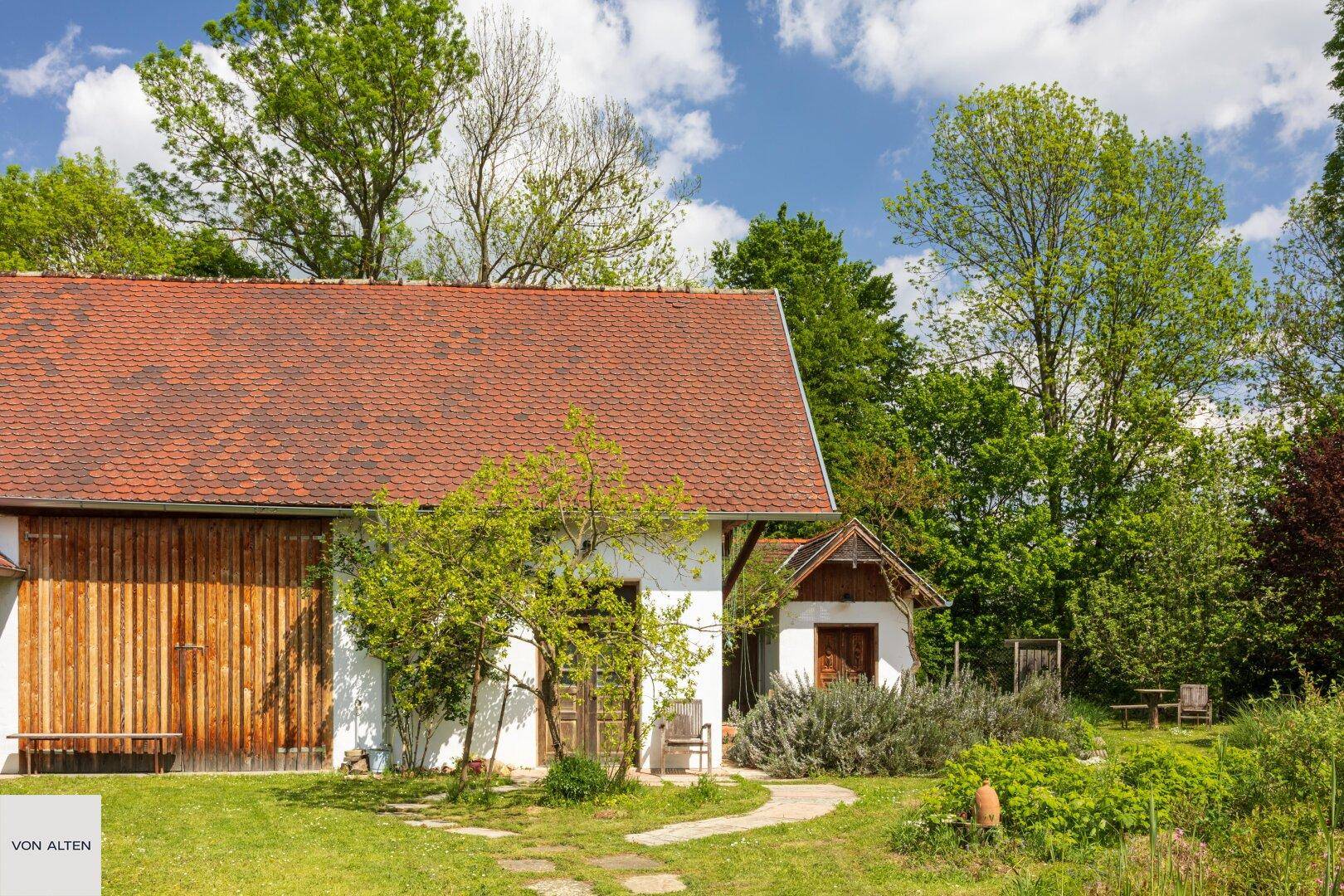 Idyllischer Gartenbereich mit Rasenfläche, Bäumen und einem kleinen Gartenhaus.