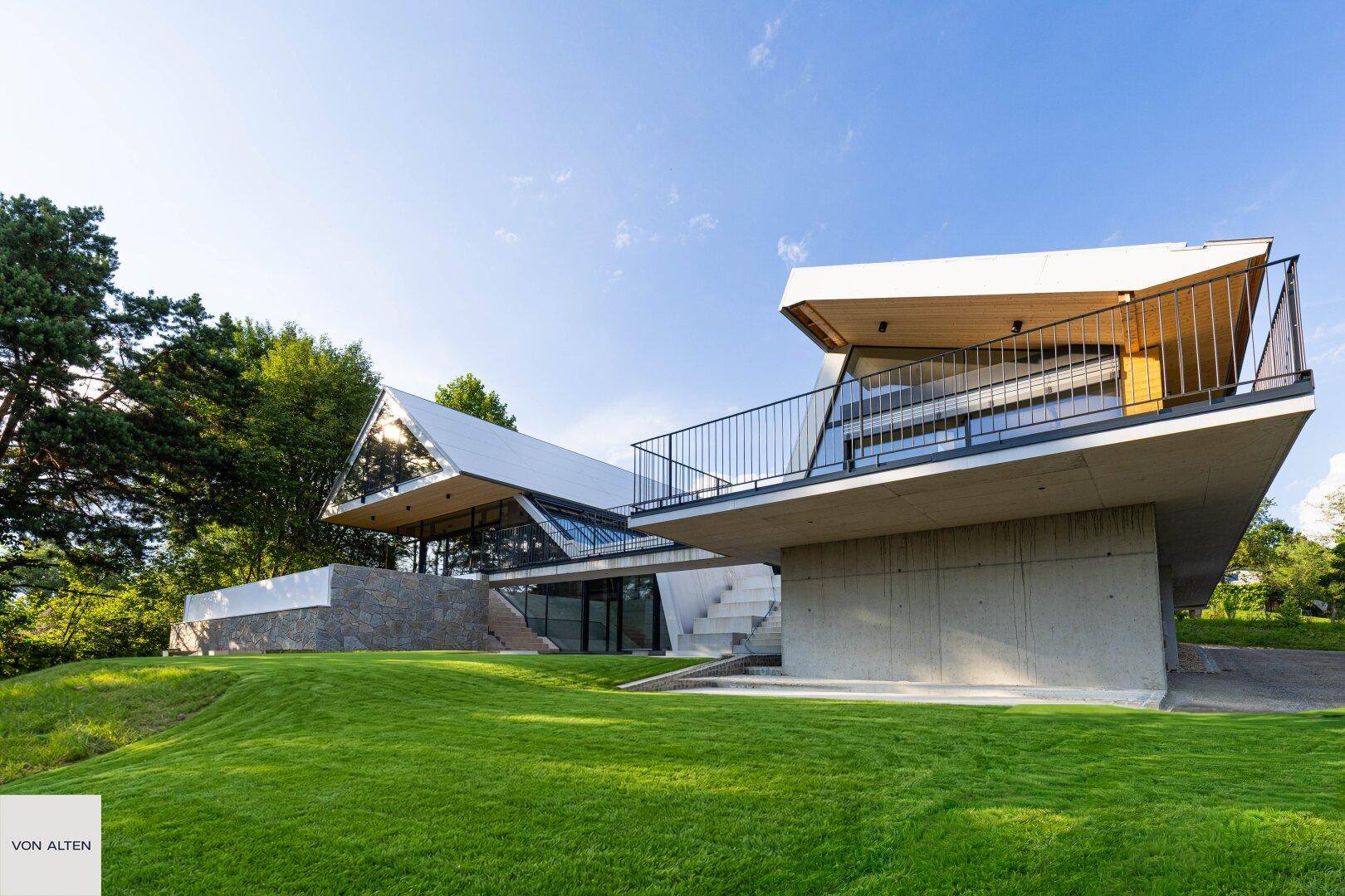 Architektonisch einzigartiges Gebäude mit markanten Linien und weitläufigen Grünflächen unter blauem Himmel.