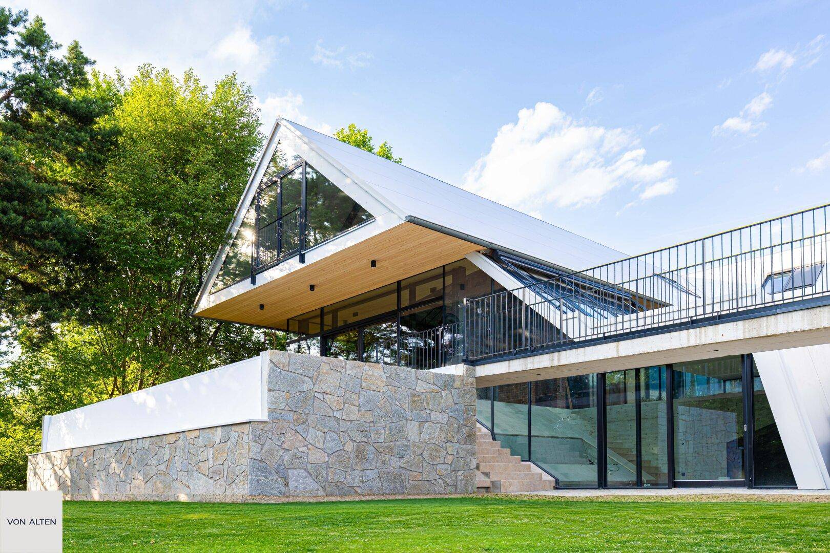 Faszinierende moderne Villa mit großen Glasfronten und einer Kombination aus Stein- und Holzmaterialien.