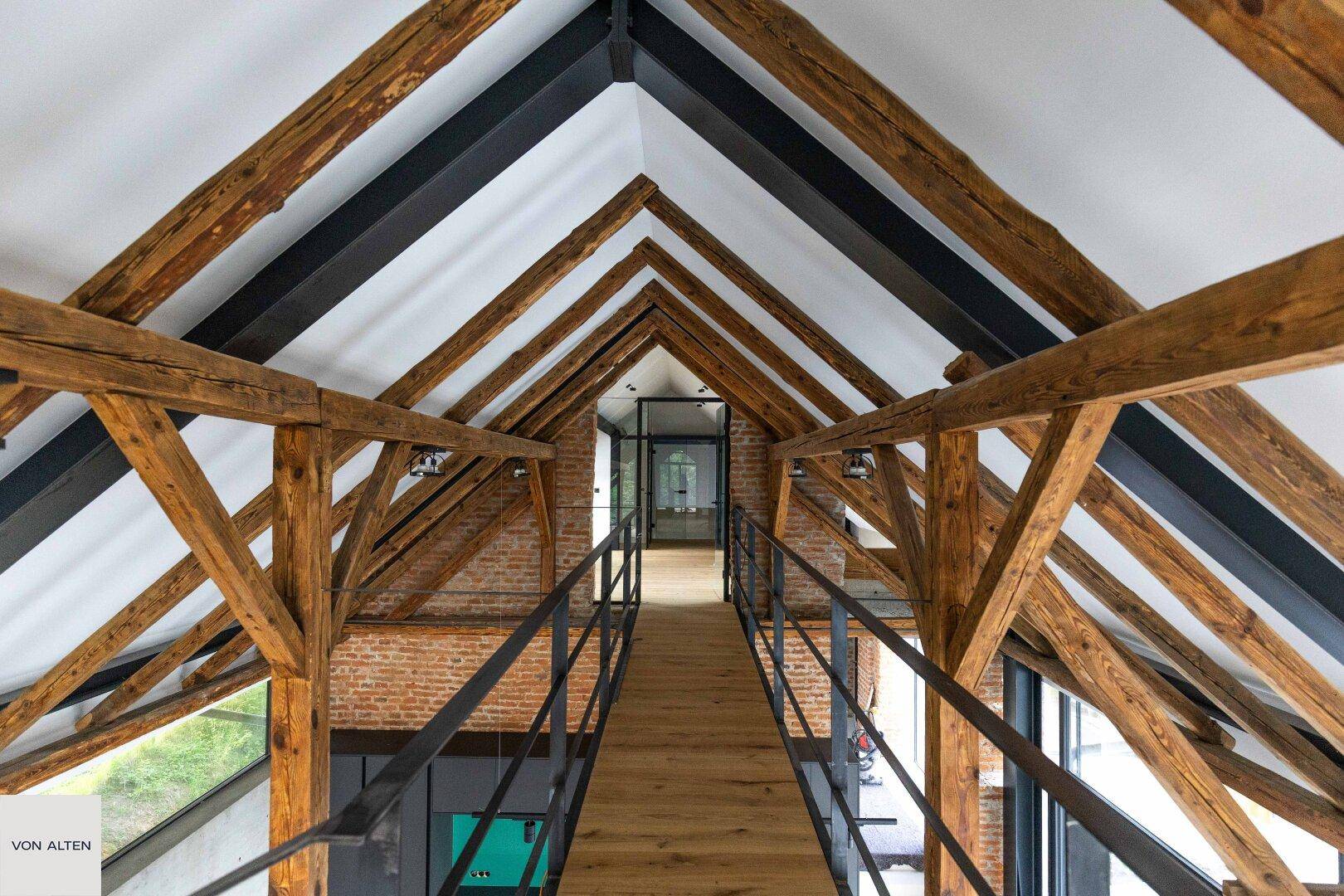 Beeindruckender Innenraum mit hohen Decken, freiliegenden Holzbalken und einer modernen Brückenkonstruktion.