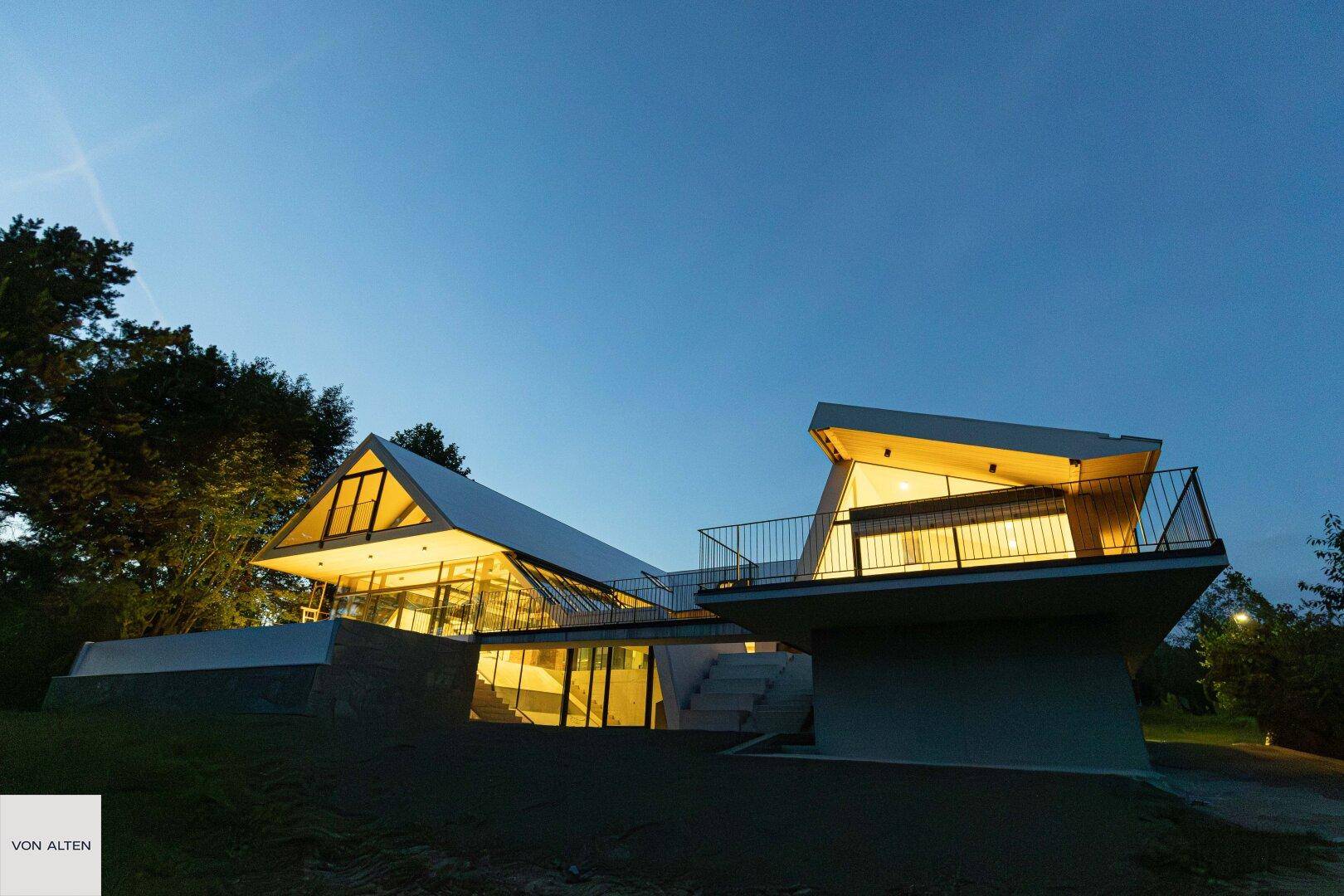 Die moderne Villa bei Nacht, eindrucksvoll beleuchtet, hebt ihre einzigartige Architektur hervor.