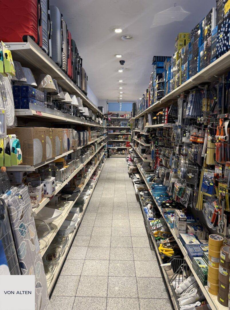 Langer Gang in einem Geschäft mit hohen Regalen, die eine Vielzahl von Produkten und Haushaltsartikeln übersichtlich präsentieren.