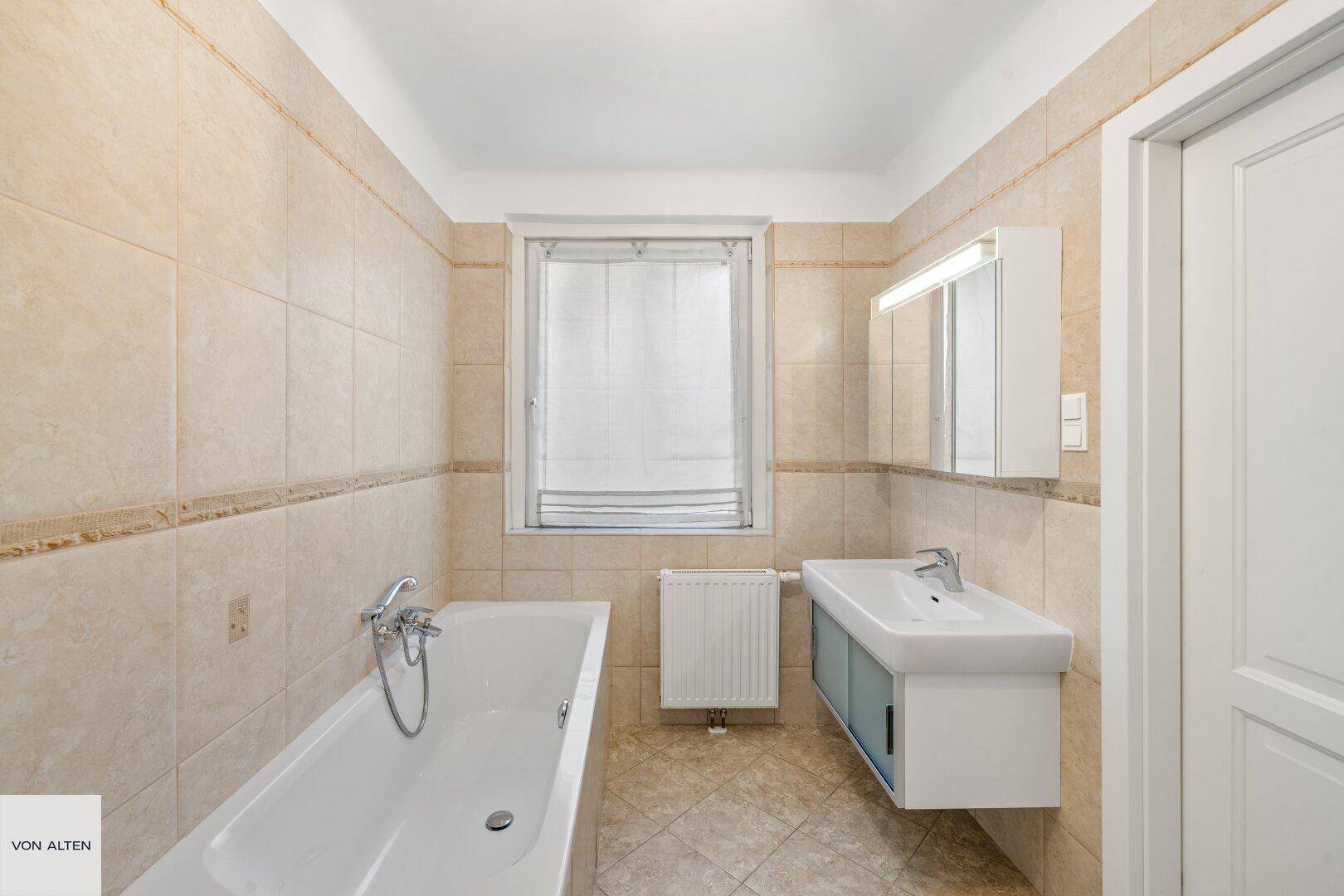 Badezimmer mit Badewanne, Waschbecken und Spiegelschrank.