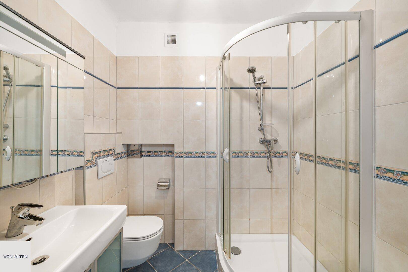 Badezimmer mit Duschkabine, Waschbecken und Toilette.