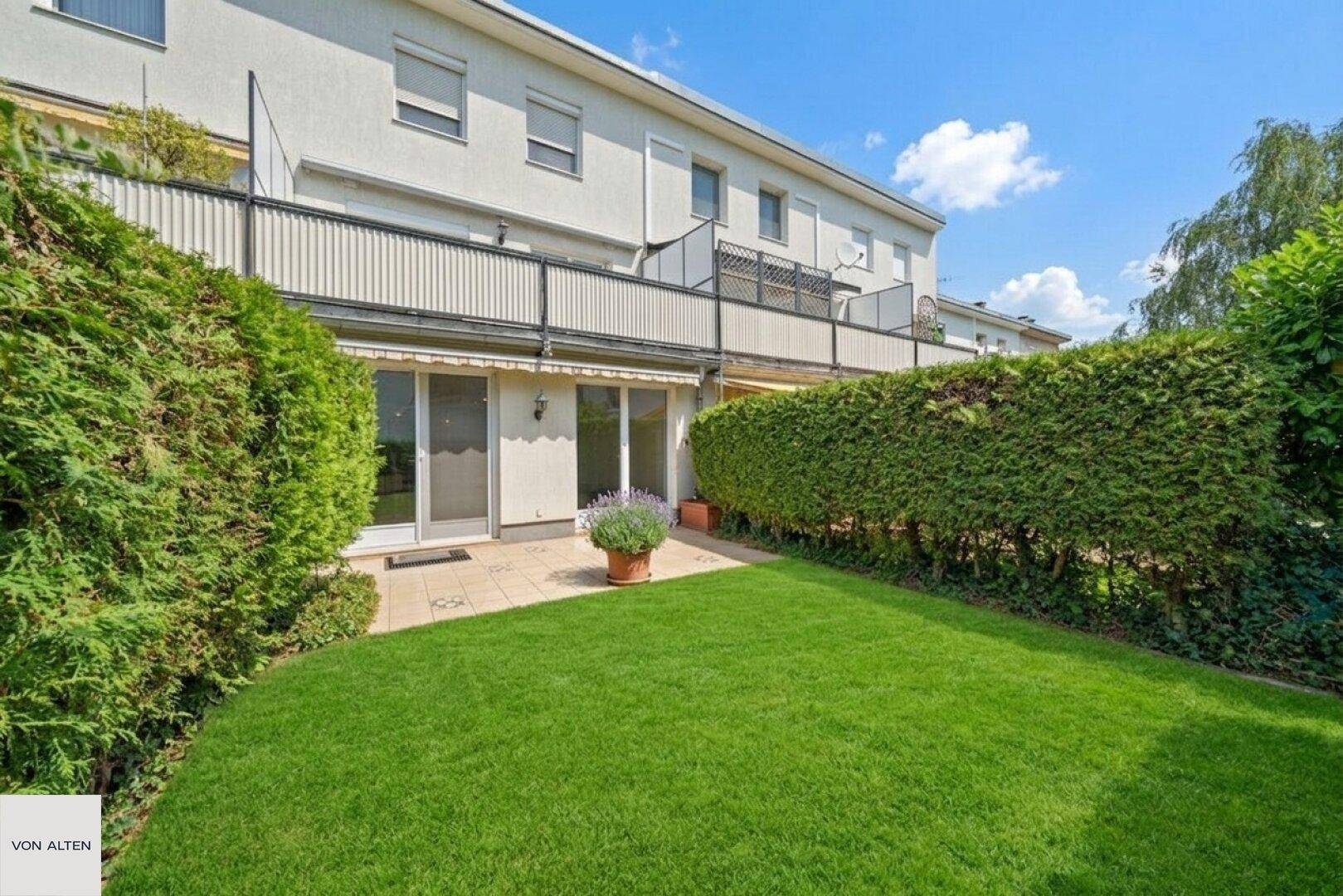 Gepflegter Garten mit Rasenfläche, Hecke und Zugang zur Terrasse.