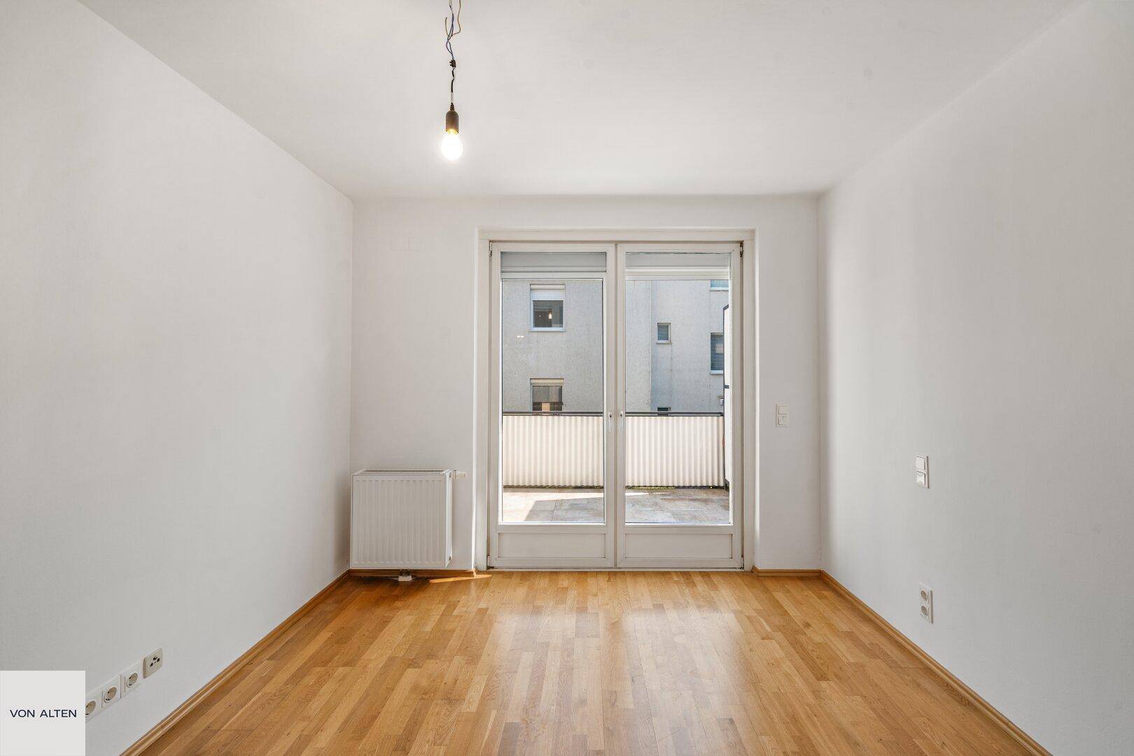 Leerer Raum mit Holzboden und Zugang zu einem Außenbereich.