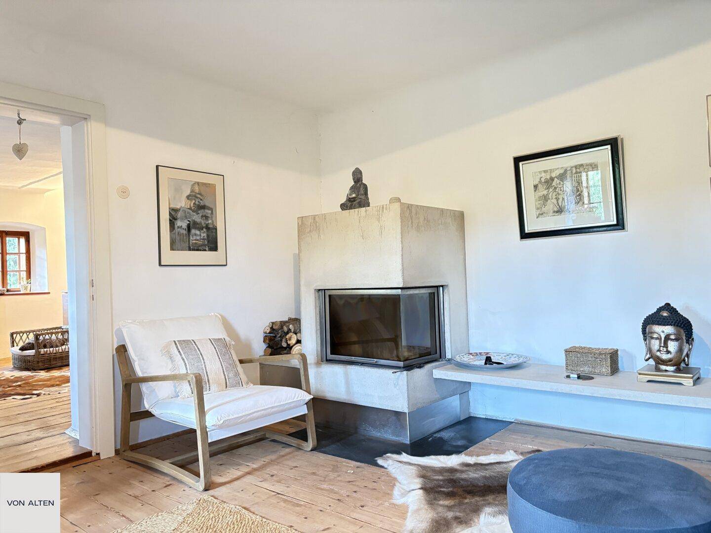 Gemütliches Wohnzimmer mit modernem Kamin, bequemen Sesseln und Holzdielenboden.