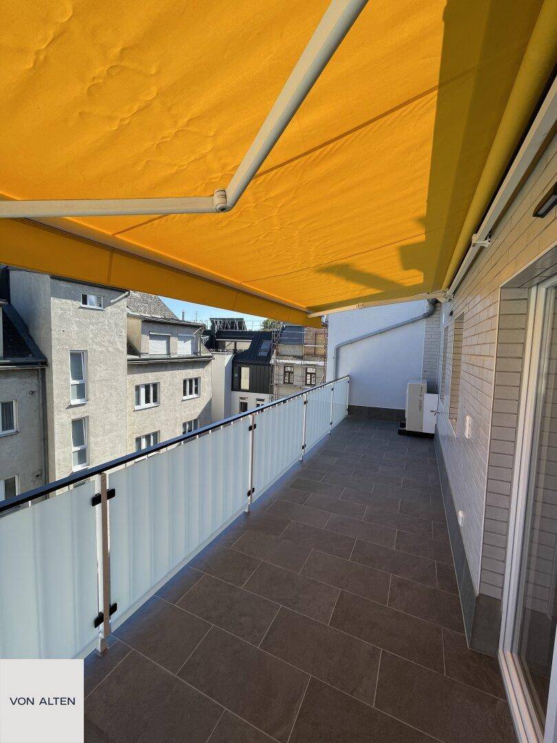 Langer Balkon mit Markise und Blick auf die umliegenden Gebäude, ideal zum Entspannen.