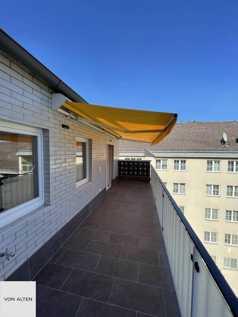 Geräumiger Balkon mit Markise und Fliesenboden, bietet Platz für Outdoor-Möbel.