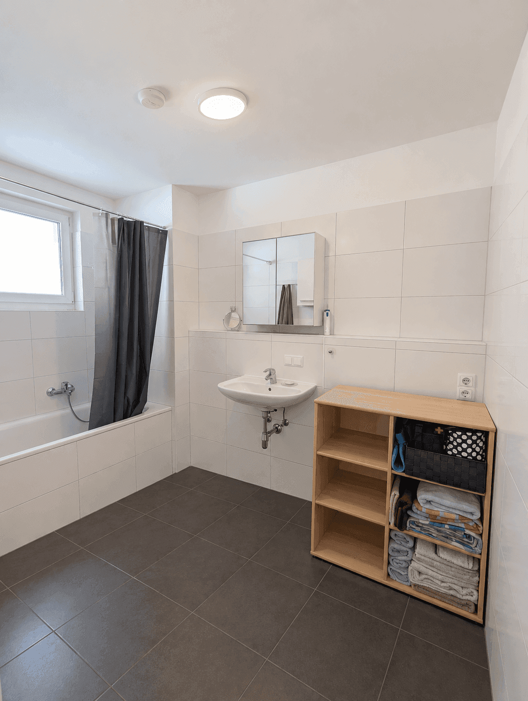 Helles Badezimmer mit Badewanne, Waschbecken und Fenster.