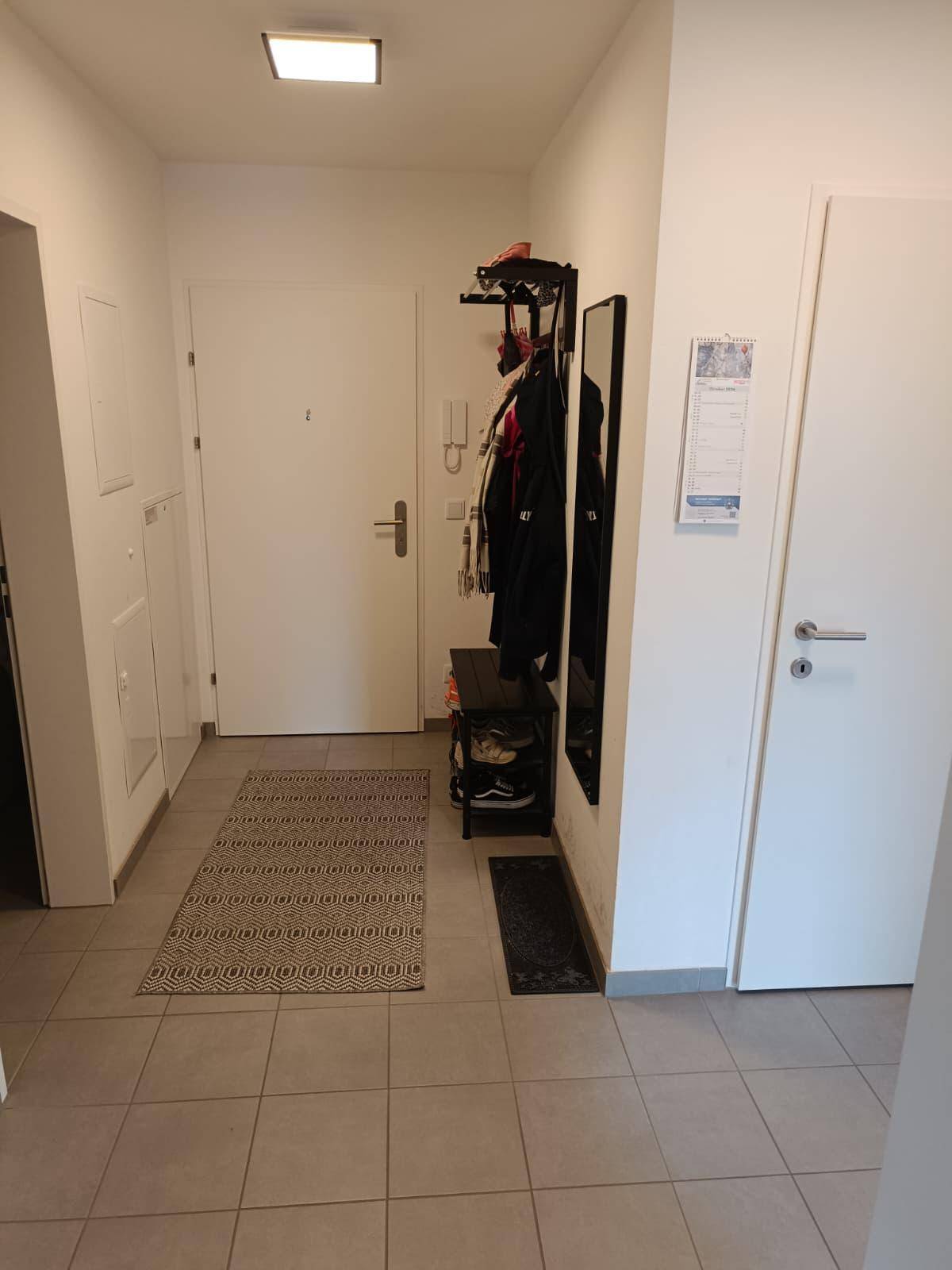 Eingangsbereich mit Fliesenboden, Garderobe und Spiegel, bietet praktischen Stauraum.