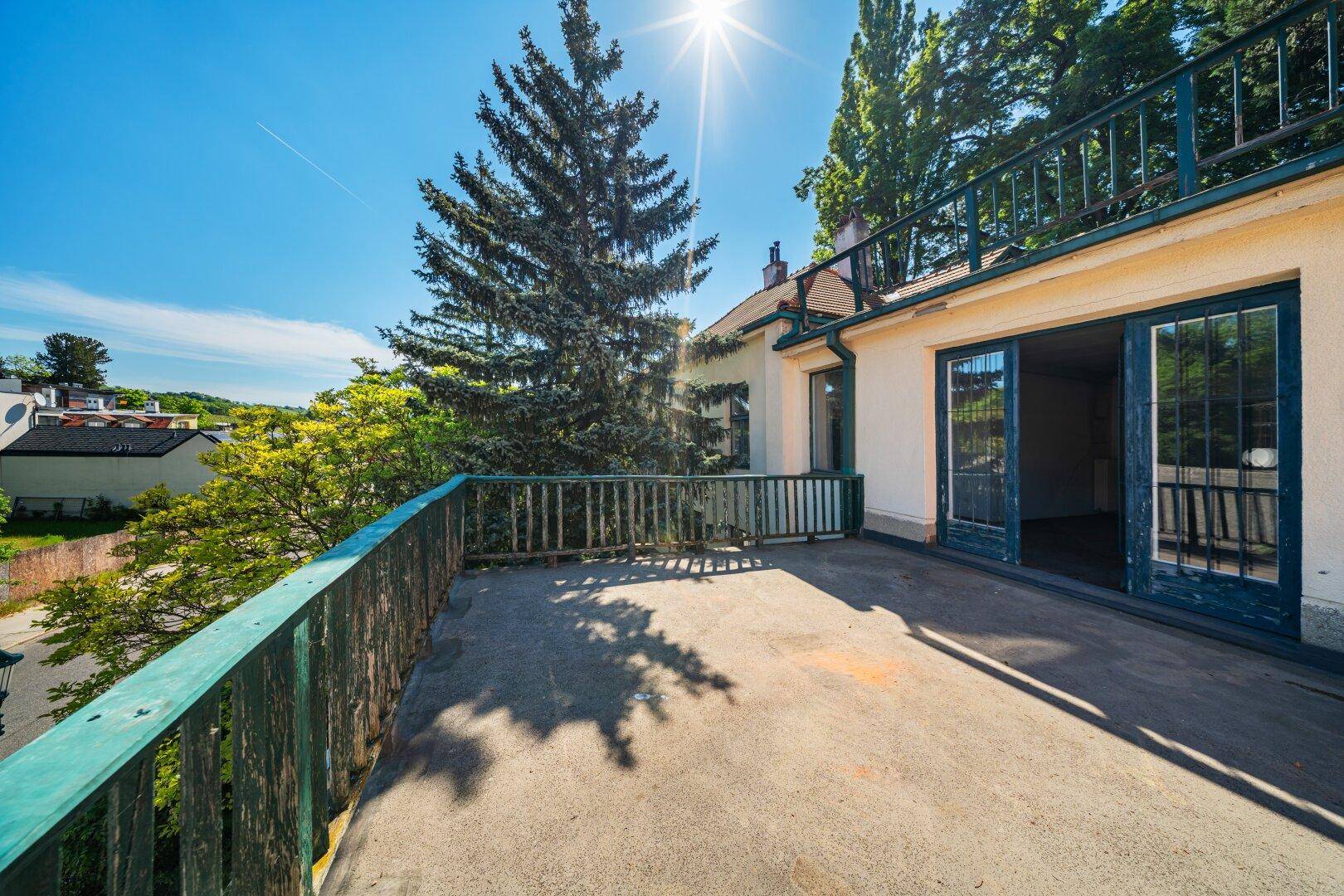 Sonnige Terrasse mit grünen Geländern, die einen weiten Blick in die Natur bietet.