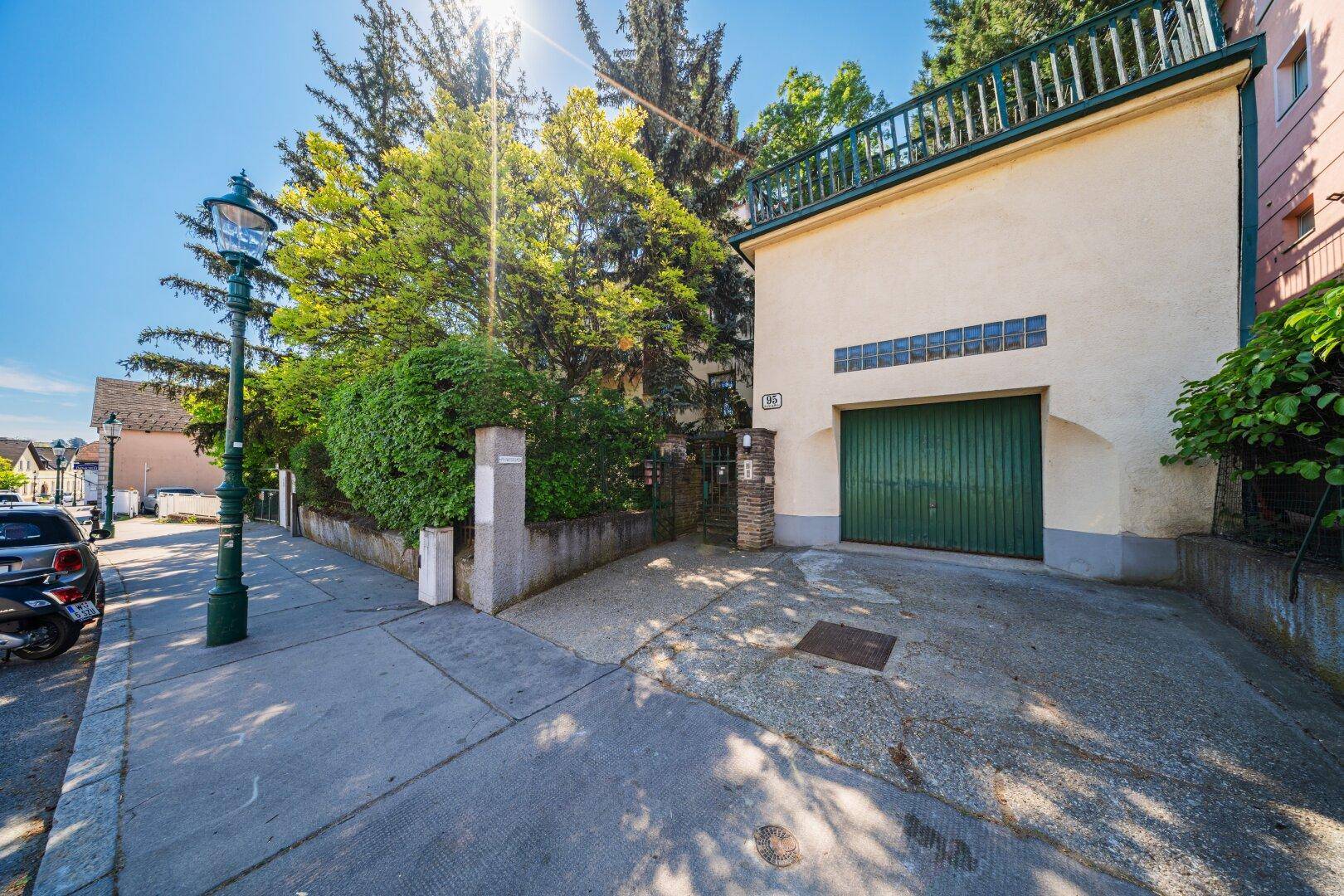 Straßenansicht des Hauses mit Garage, Einfahrt und Parkmöglichkeiten an der Straße.