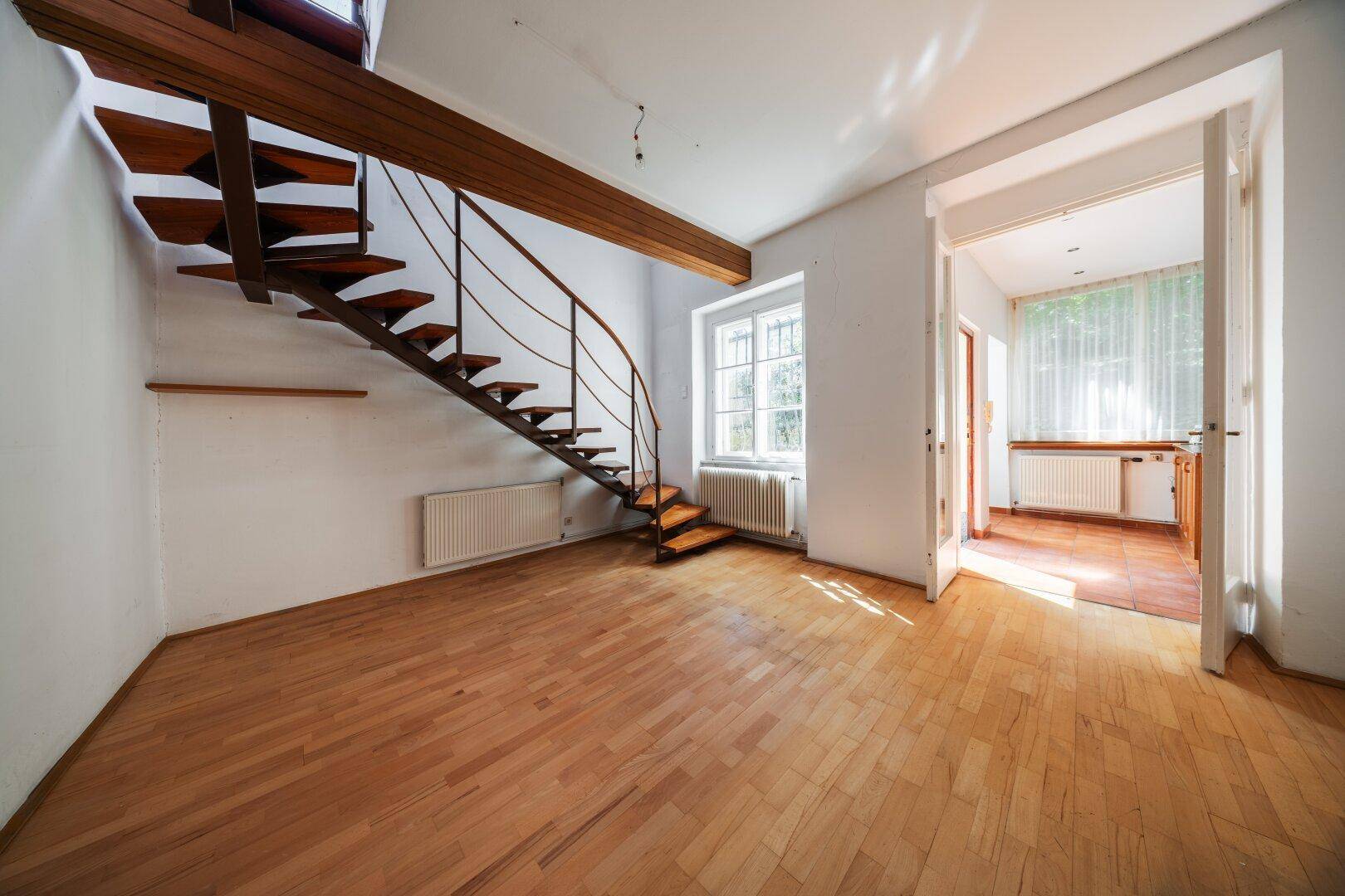 Helles Zimmer mit Holzparkettboden und einer eleganten Wendeltreppe.