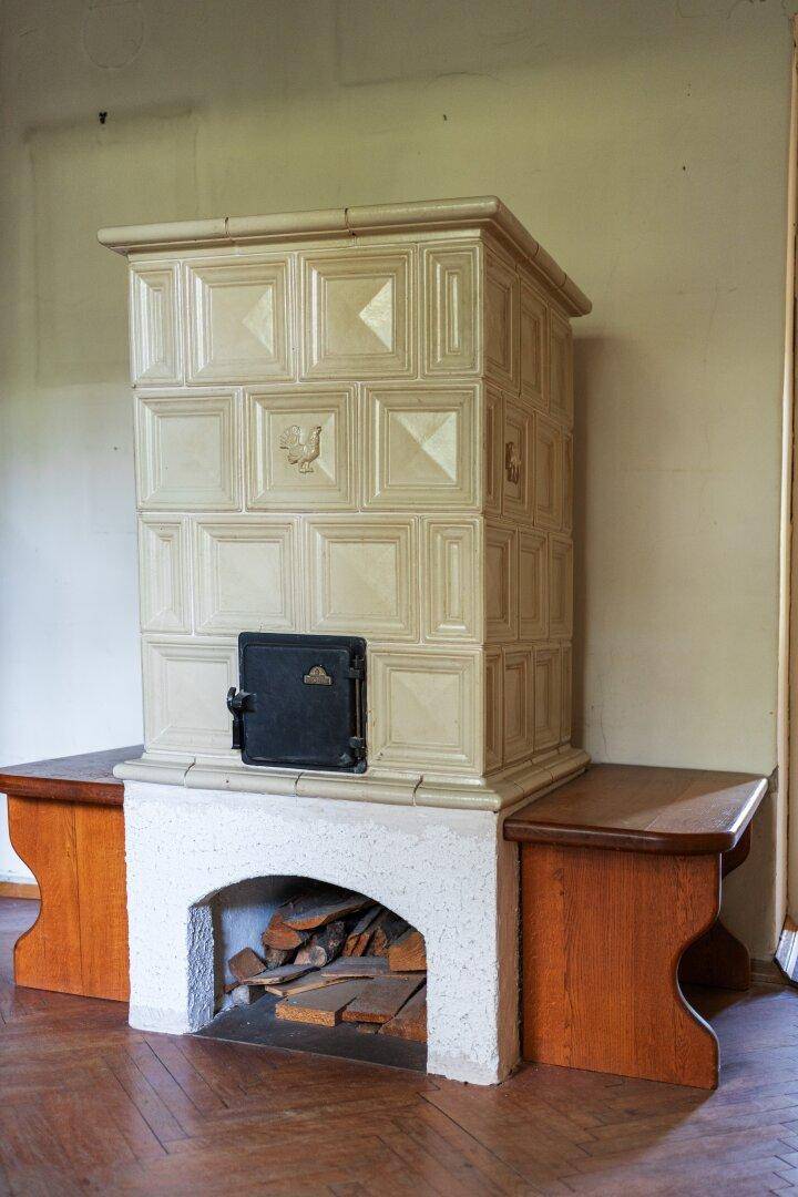 Traditioneller Kachelofen mit Holzbänken in einem Raum mit Parkettboden.