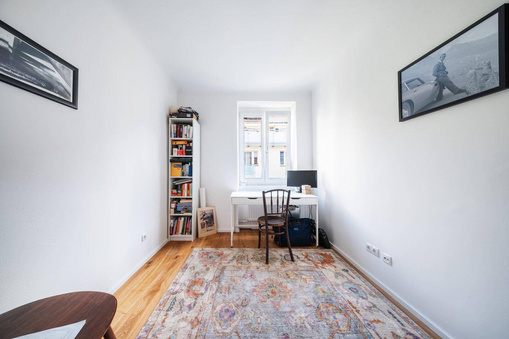 Helles Arbeitszimmer mit Schreibtisch, Bücherregal und Holzboden, ideal für Home-Office.
