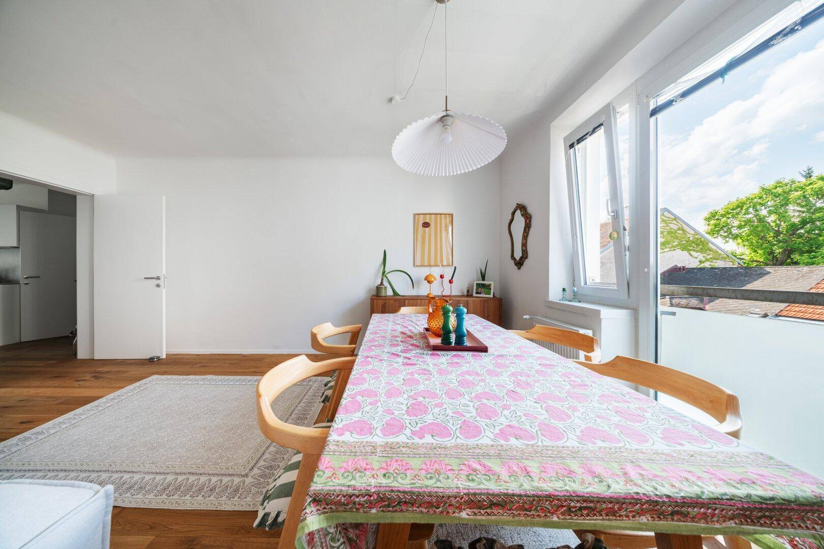 Essbereich mit großem Tisch, bunten Tischdecken und Zugang zu einem Balkon.
