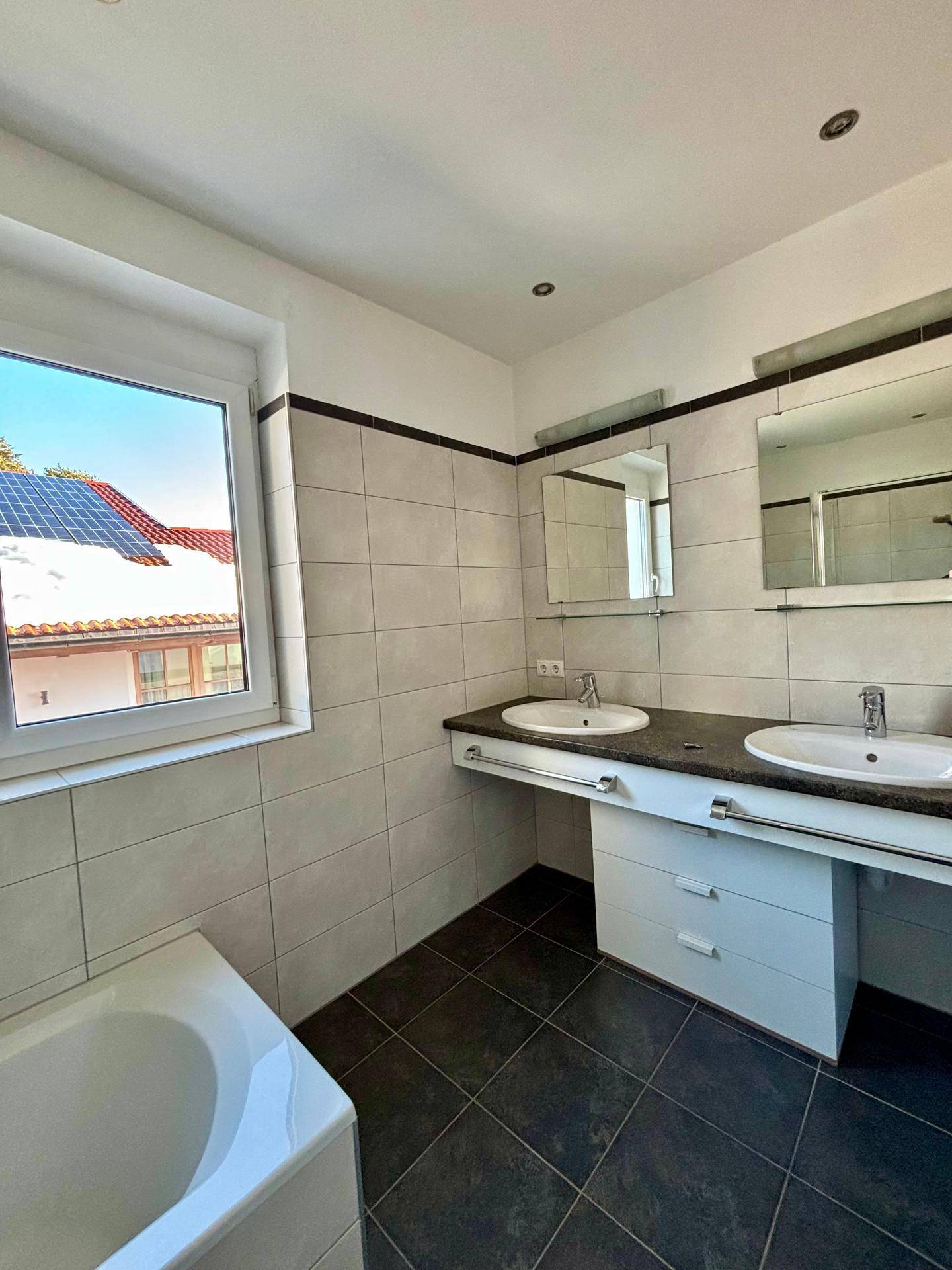 Geräumiges Badezimmer mit Doppelwaschbecken, Badewanne und Fenster.