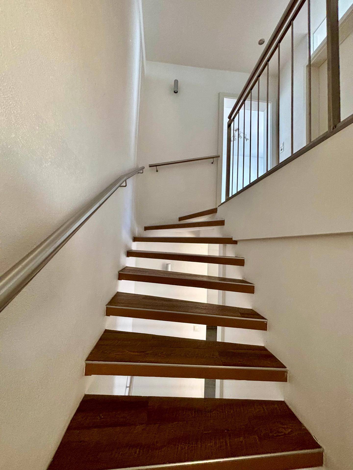 Moderne Holztreppe mit Edelstahlgeländer verbindet die Stockwerke des Hauses.