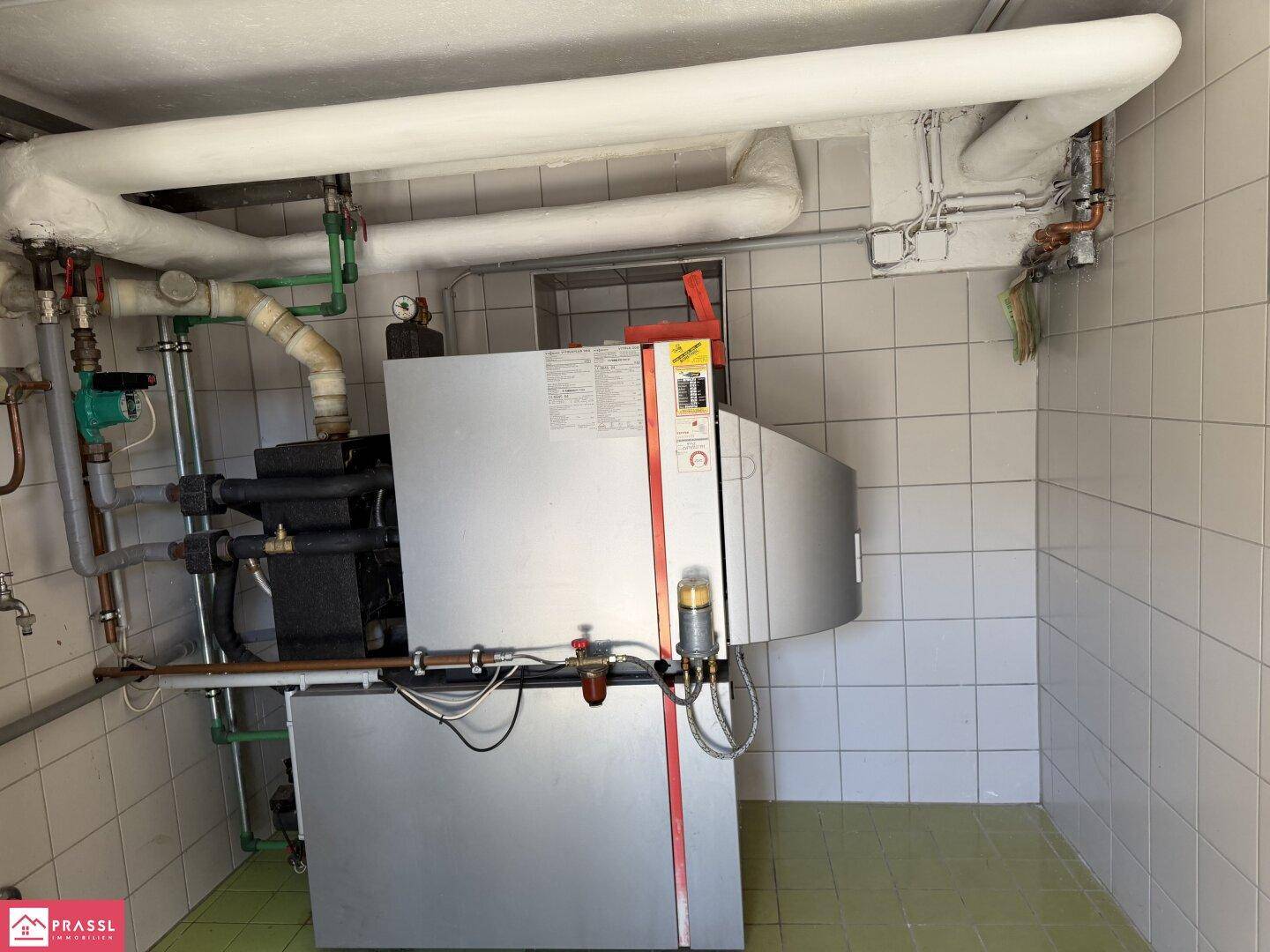 Heizungsraum mit Kesselanlage und gefliesten Wänden.