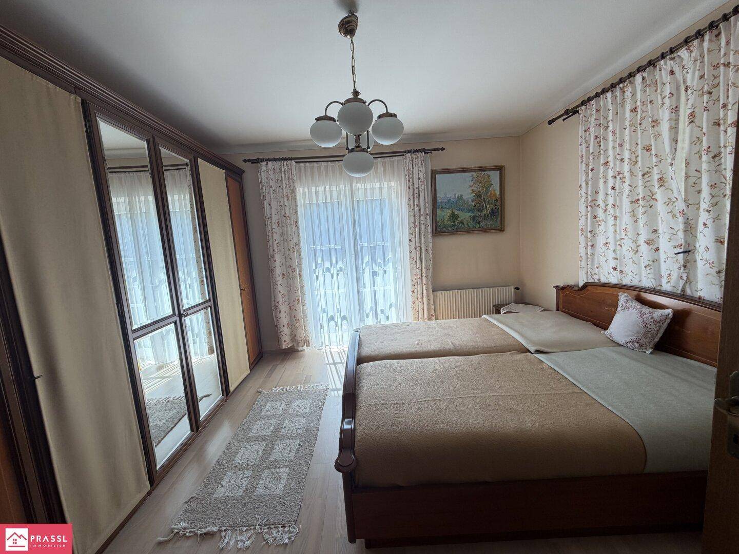 Schlafzimmer mit Doppelbett, großem Spiegelschrank und Zugang zum Balkon.