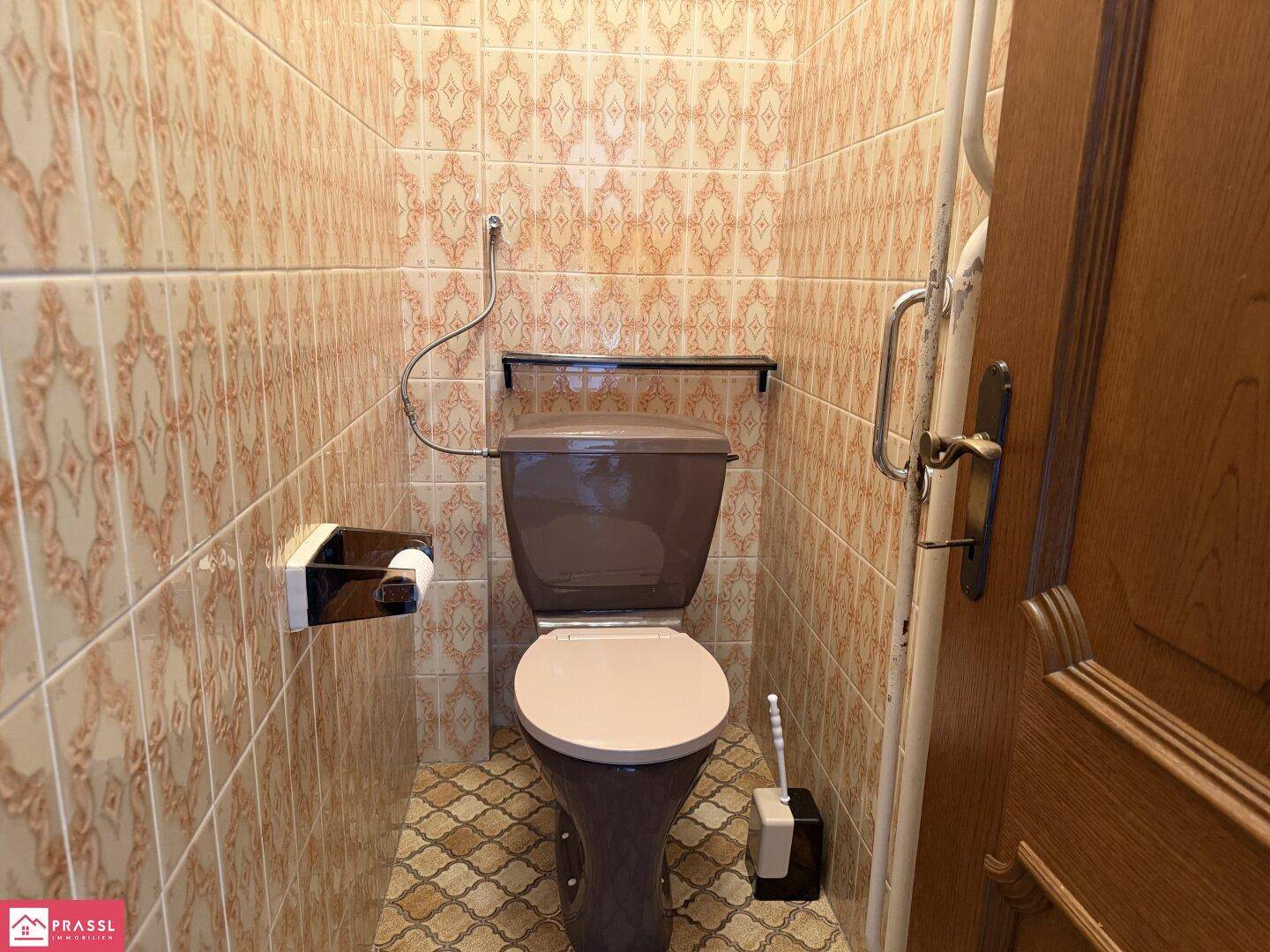 Kleines WC mit gemusterten Fliesen und traditioneller Ausstattung.