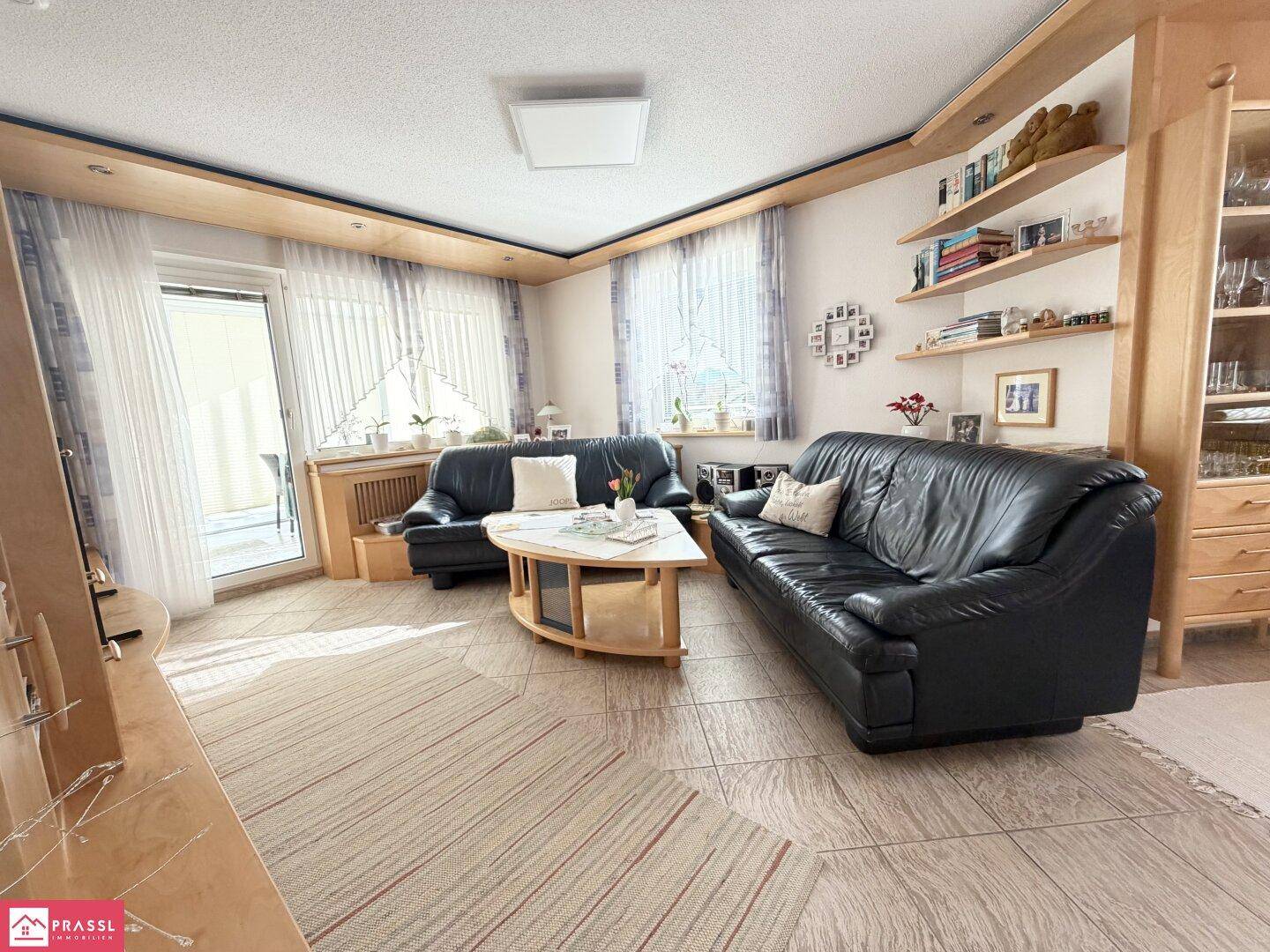 Geräumiges Wohnzimmer mit Ledersofas, Holzelementen und Zugang zu einem Außenbereich.