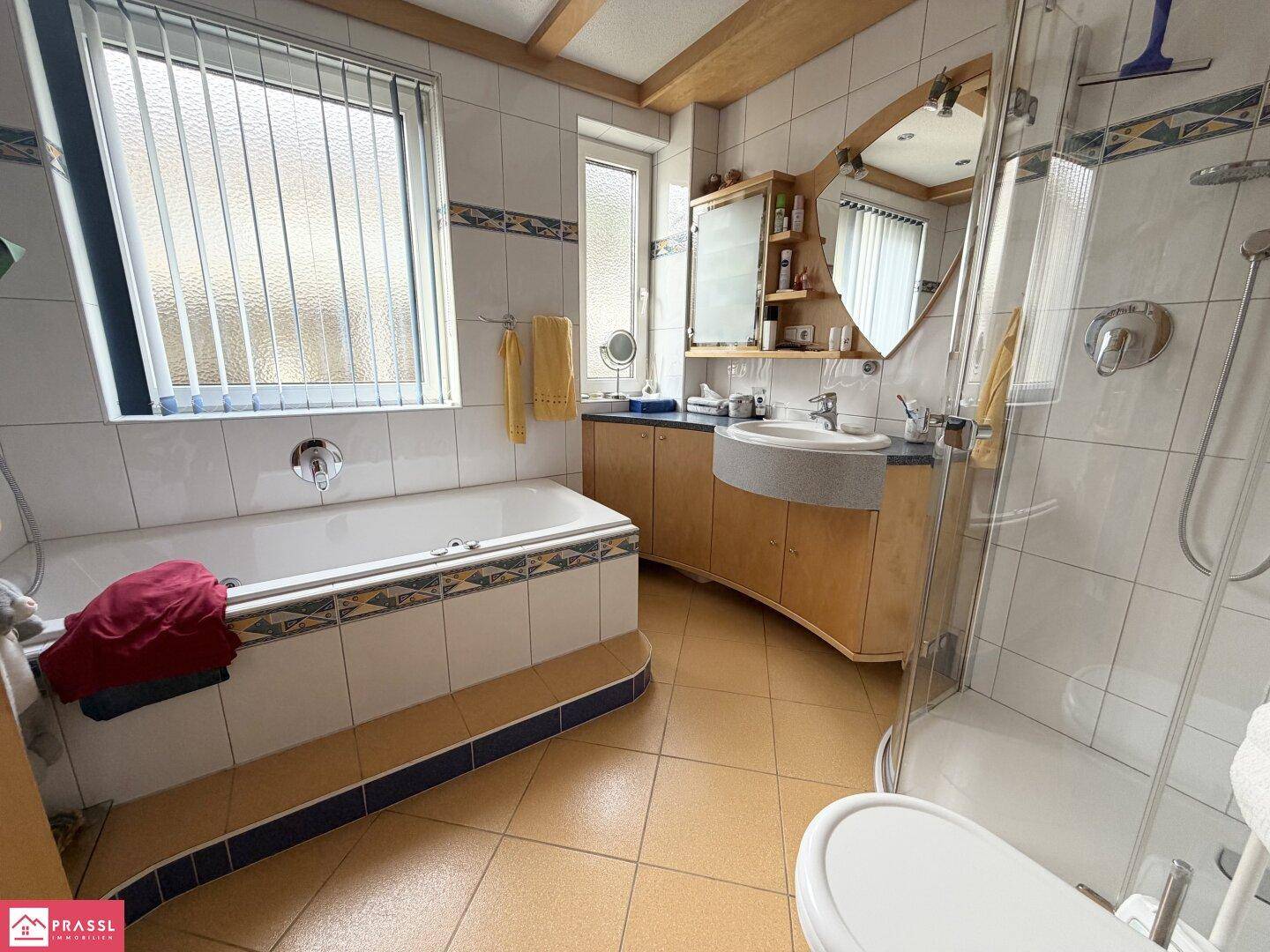 Geräumiges Badezimmer mit Badewanne, separater Dusche und Holzwaschtisch.