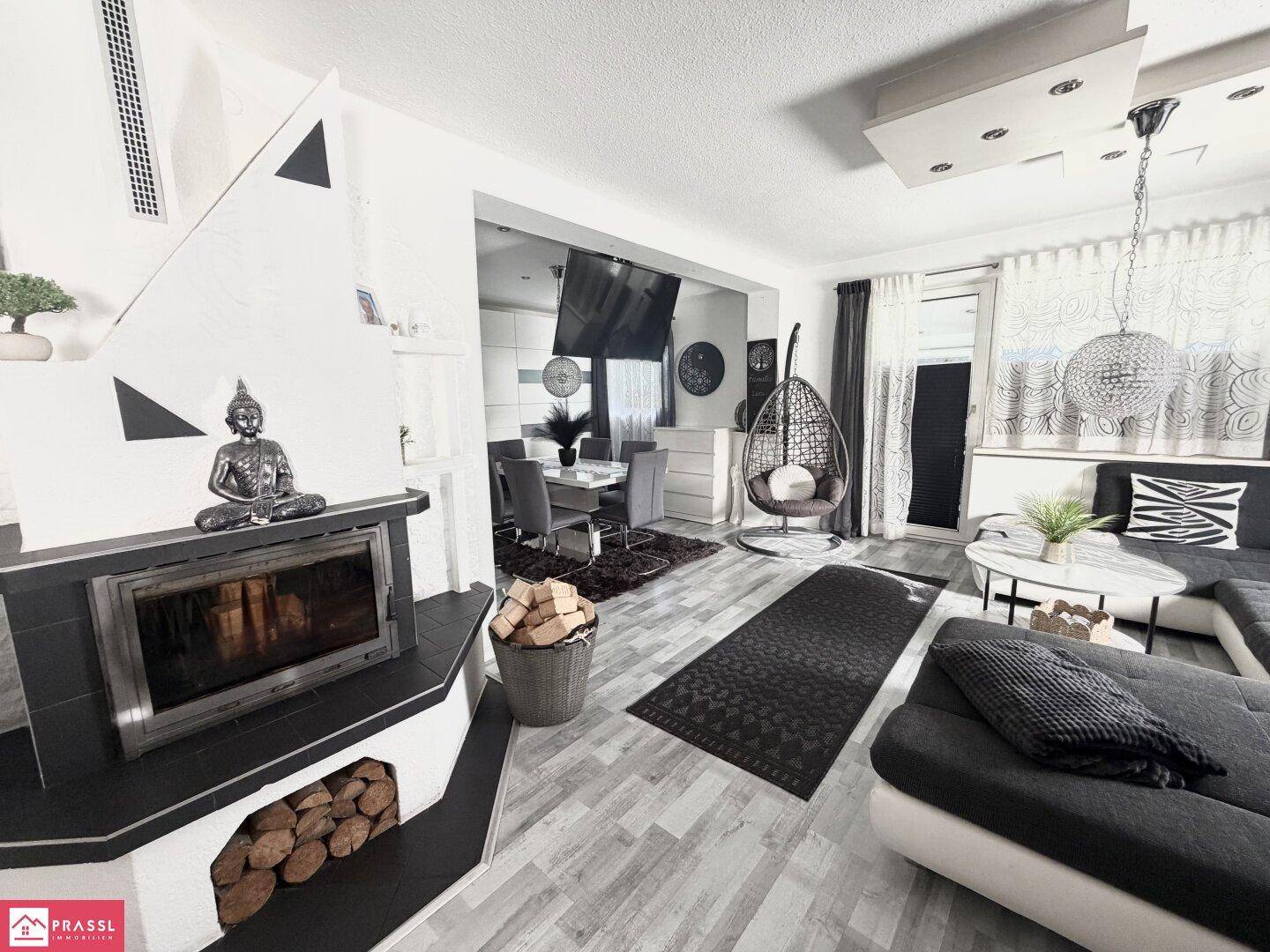 Gemütlicher Wohnbereich mit Kamin, modernem Sofa und Essbereich im Hintergrund.