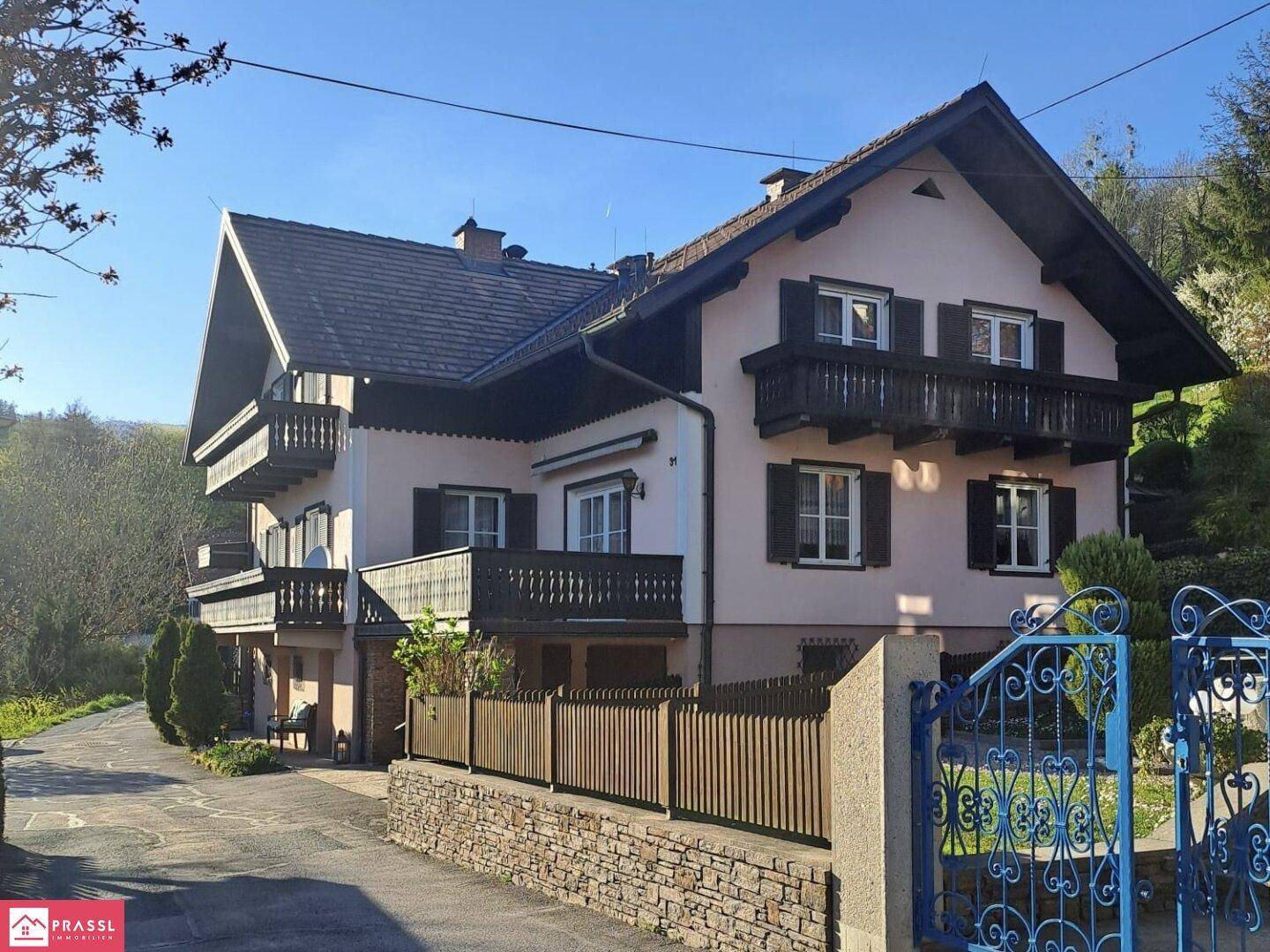 Traditionelles Wohnhaus mit mehreren Balkonen und einem schmiedeeisernen Tor in ländlicher Umgebung.