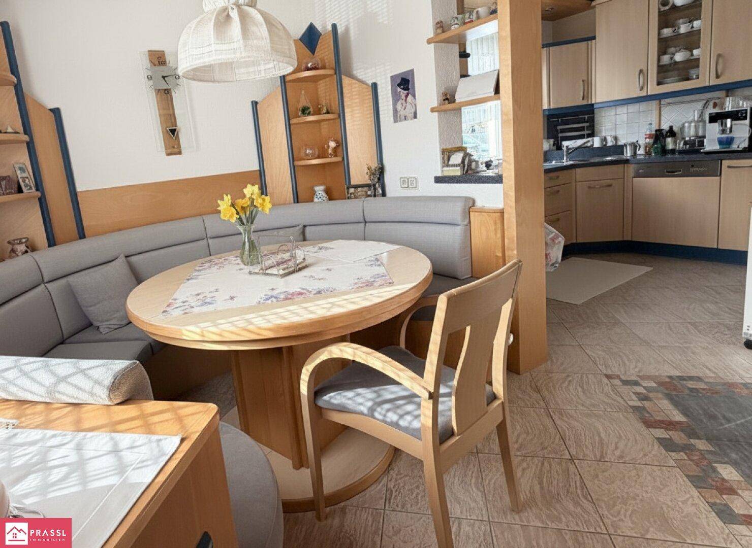 Traditionelle Wohnküche mit Eckbank, Esstisch und funktionaler Küchenzeile im Hintergrund.