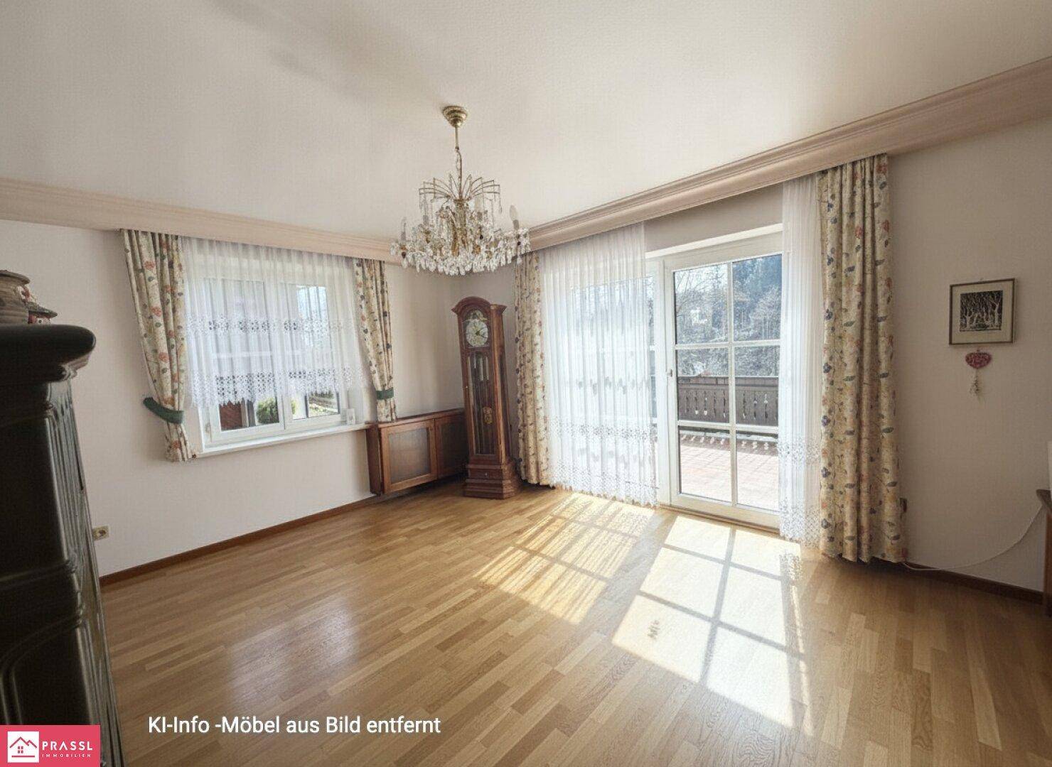 Lichtdurchflutetes Wohnzimmer mit Parkettboden, Kronleuchter und Balkonzugang.