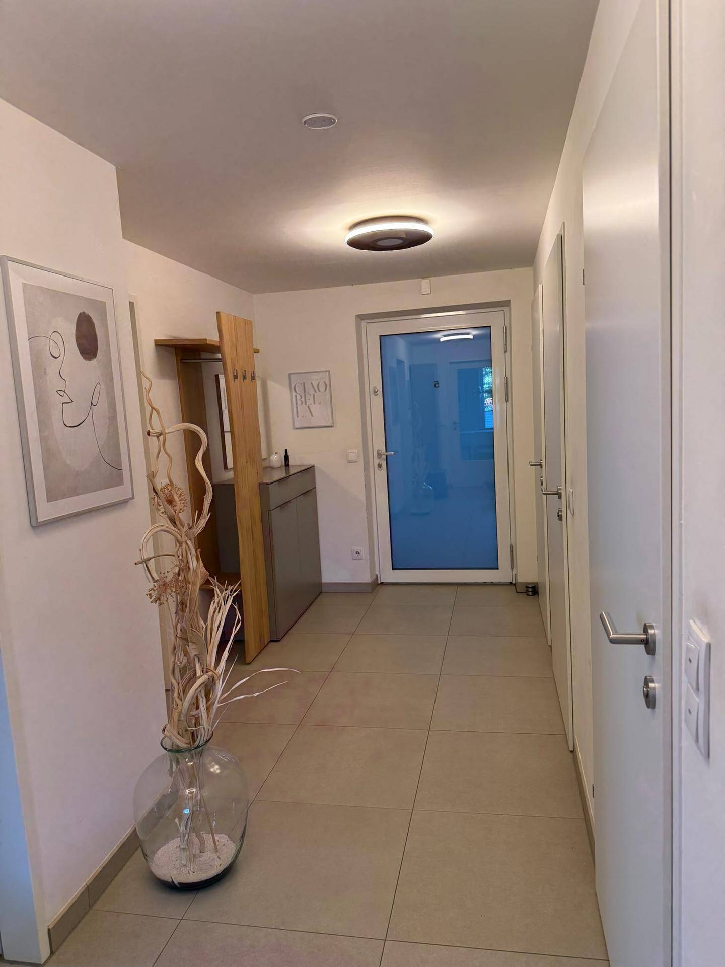 Eingangsbereich mit Fliesenboden, Garderobe und heller Eingangstür.